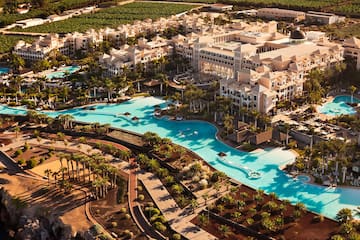 a large hotel with a pool and palm trees