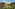 Large white Italian villa on hill, terraced gardens, cypress trees, winding road.