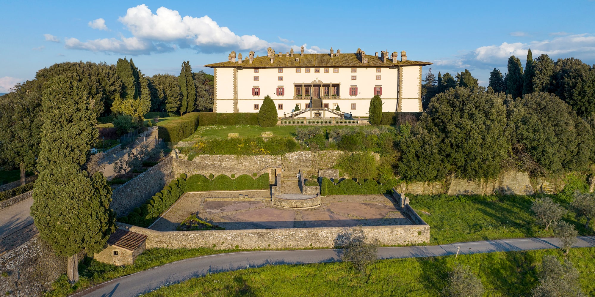 a large white building with a stone wall and a courtyard