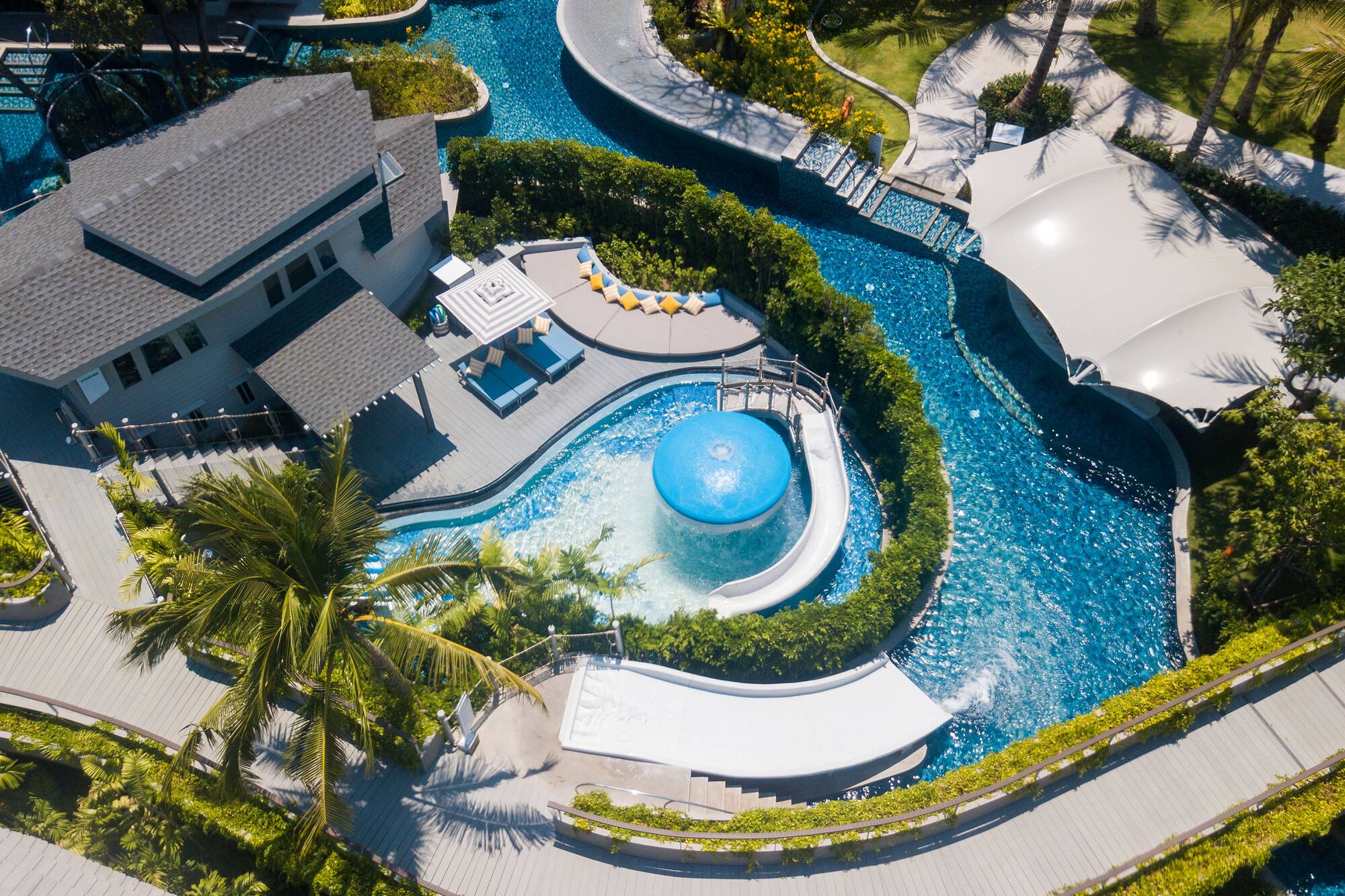 Tropical resort aerial: winding pools, waterslides, and luxurious villas.