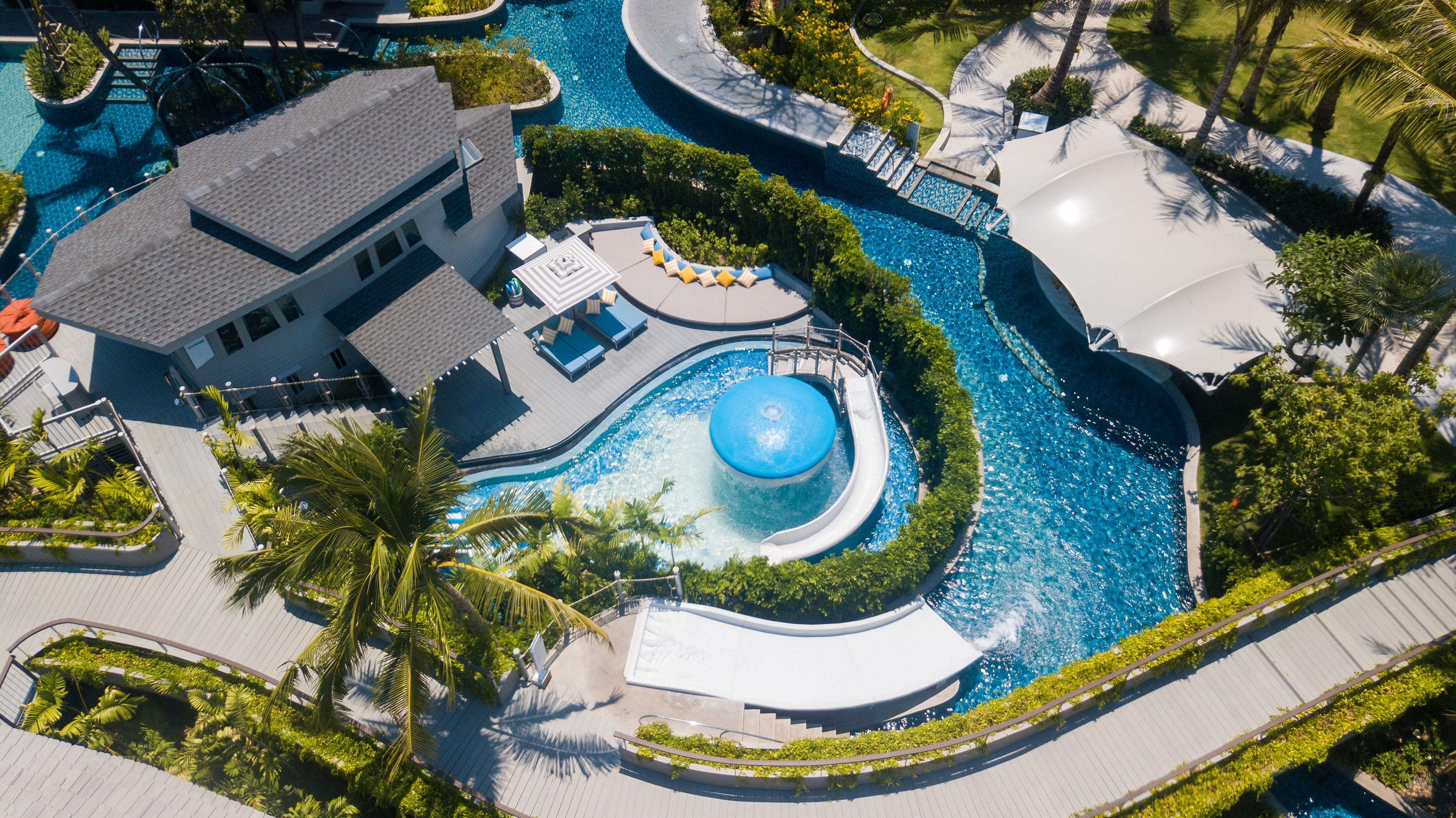 Tropical resort aerial: winding pools, waterslides, and luxurious villas.
