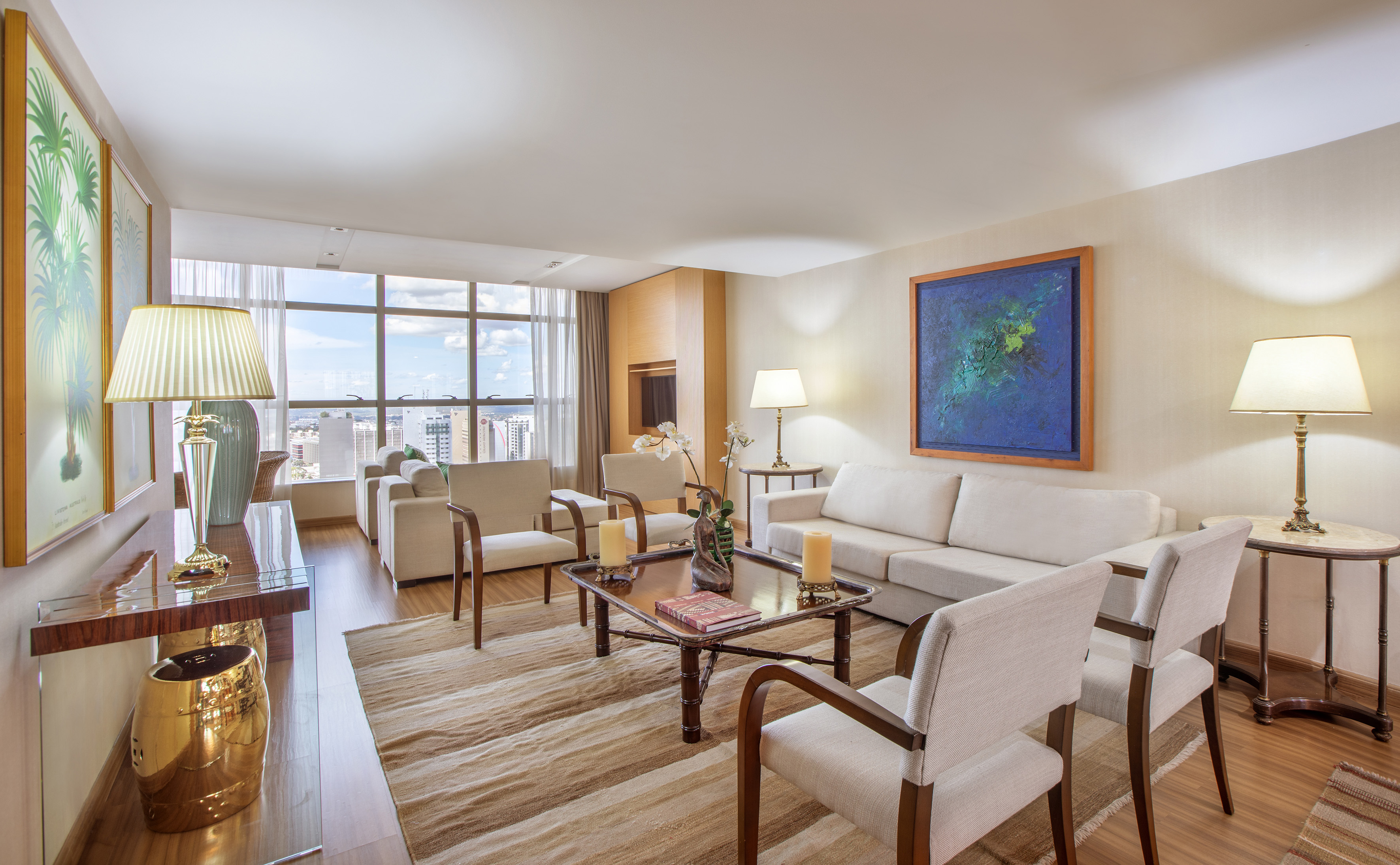 Spacious modern living room with city view, white sofas, and elegant decor.