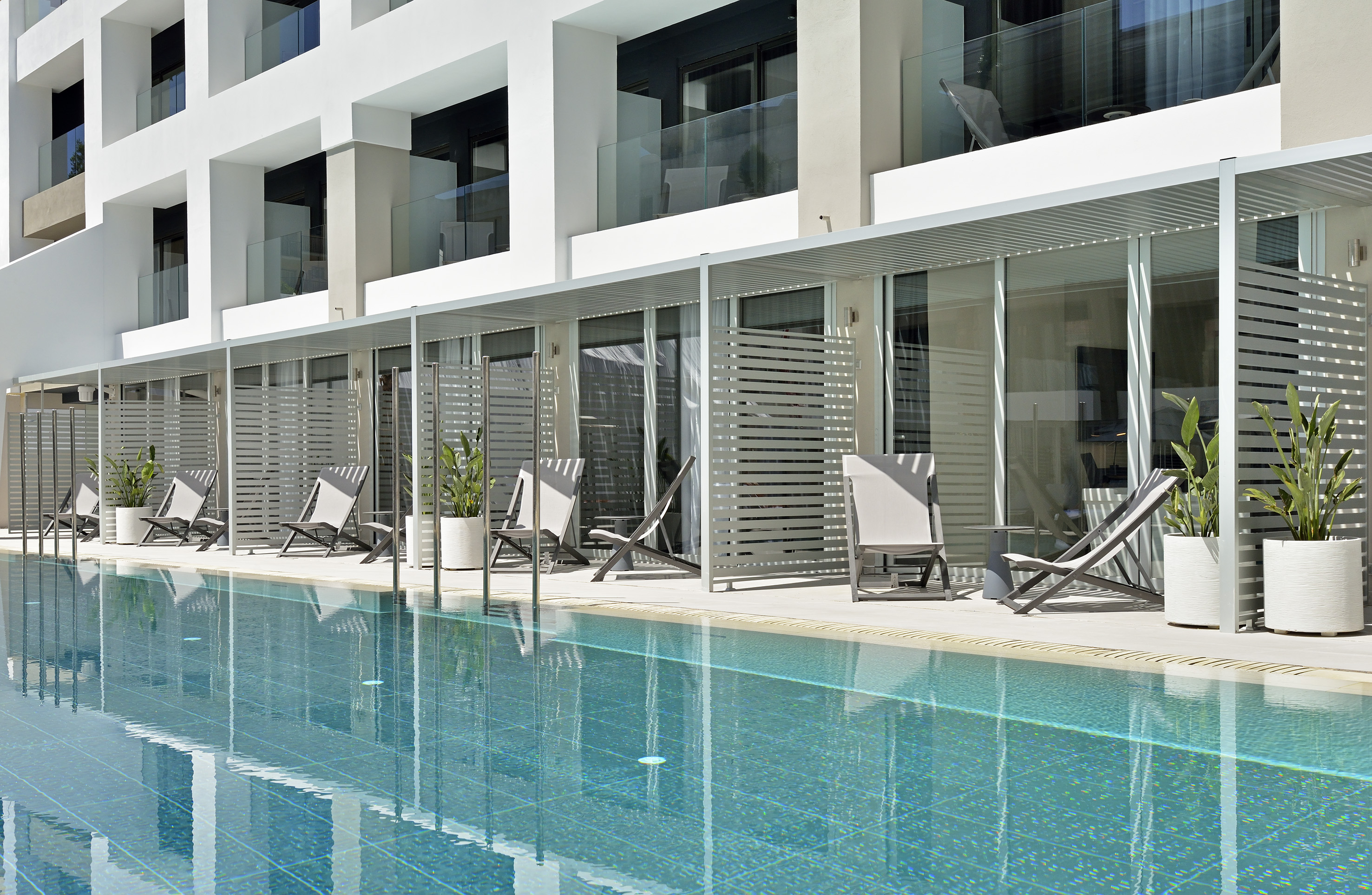 Modern hotel with swim-up rooms, lounge chairs, and outdoor pool.
