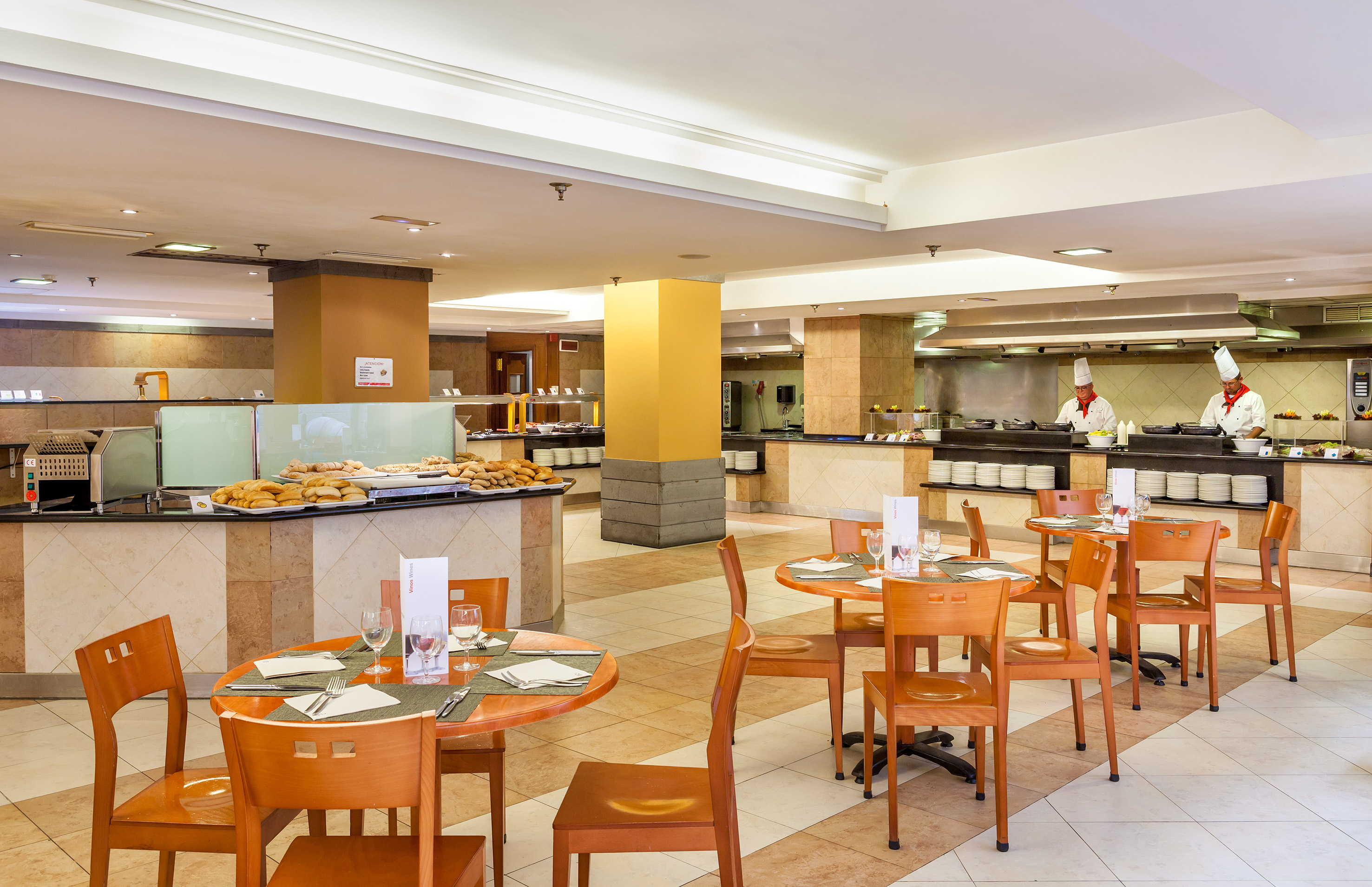 Hotel buffet restaurant with chefs, breakfast food, and dining tables.