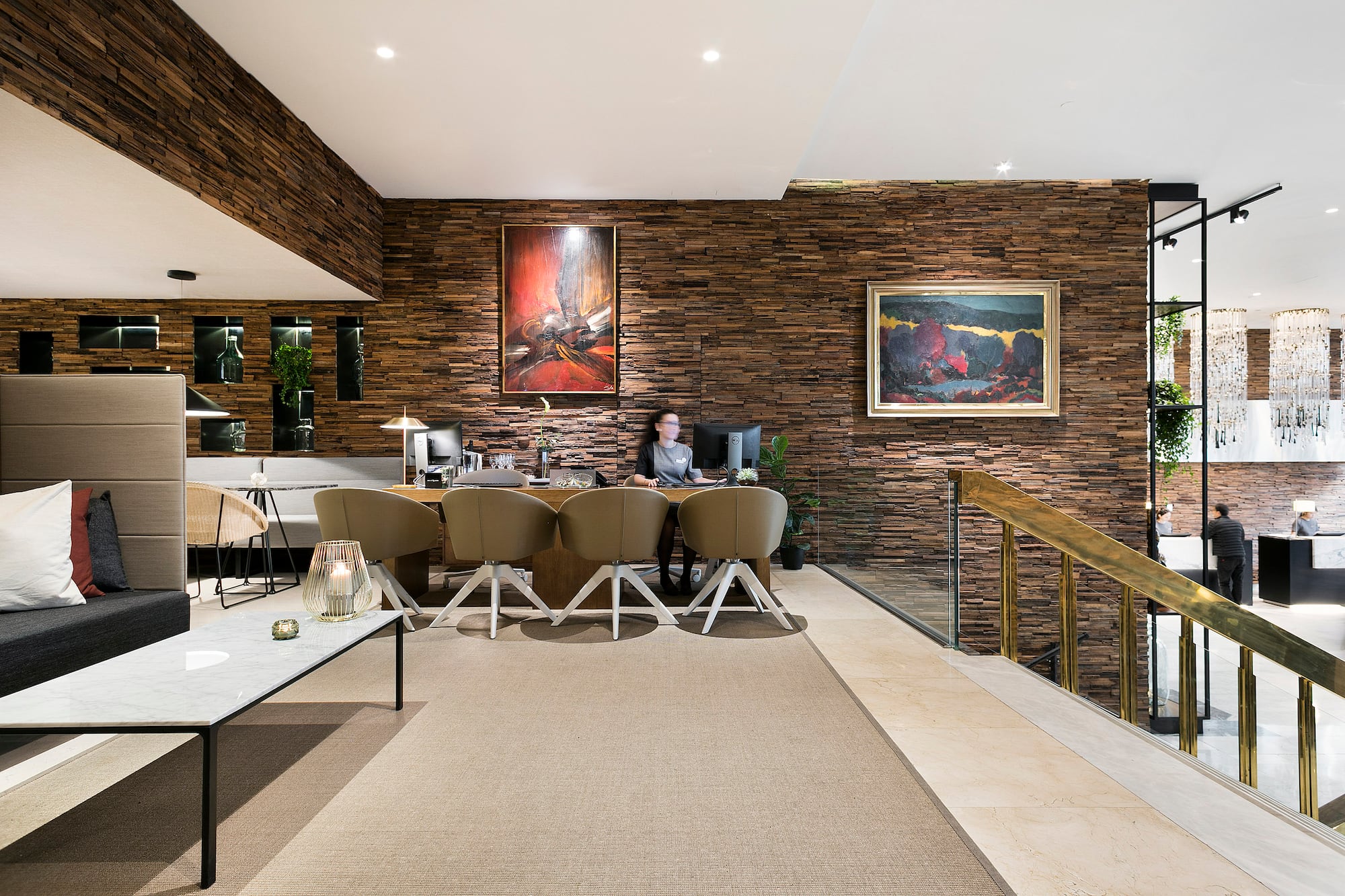 a woman sitting at a desk in a room with a stone wall