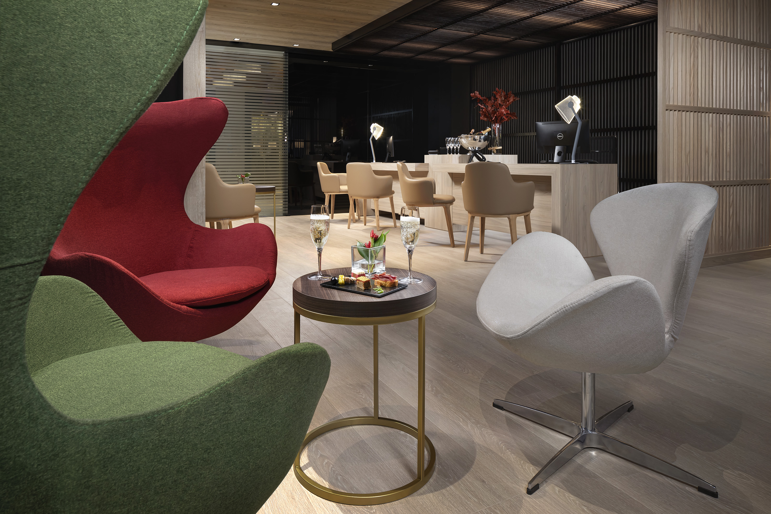 Vibrant modern lounge with red and green chairs, champagne, and hotel reception.