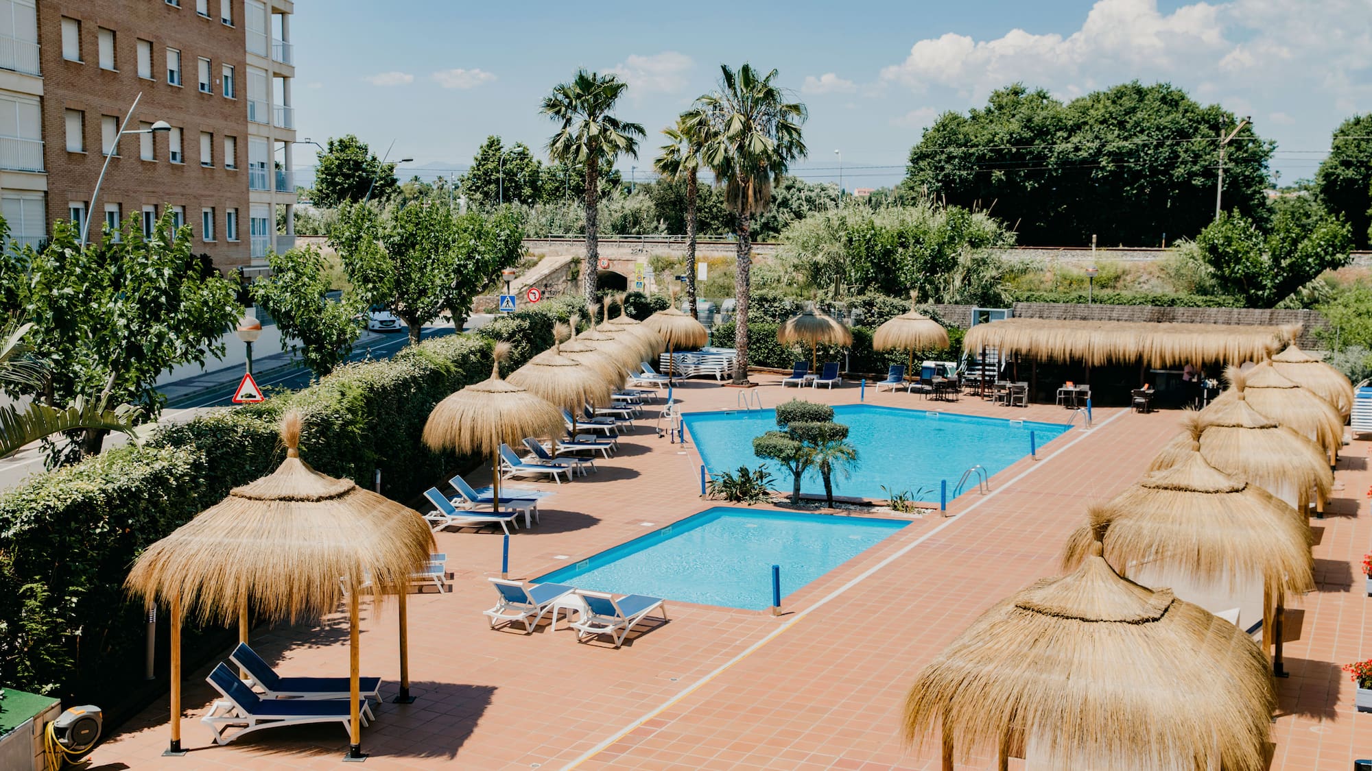 a pool with straw umbrellas and chairs