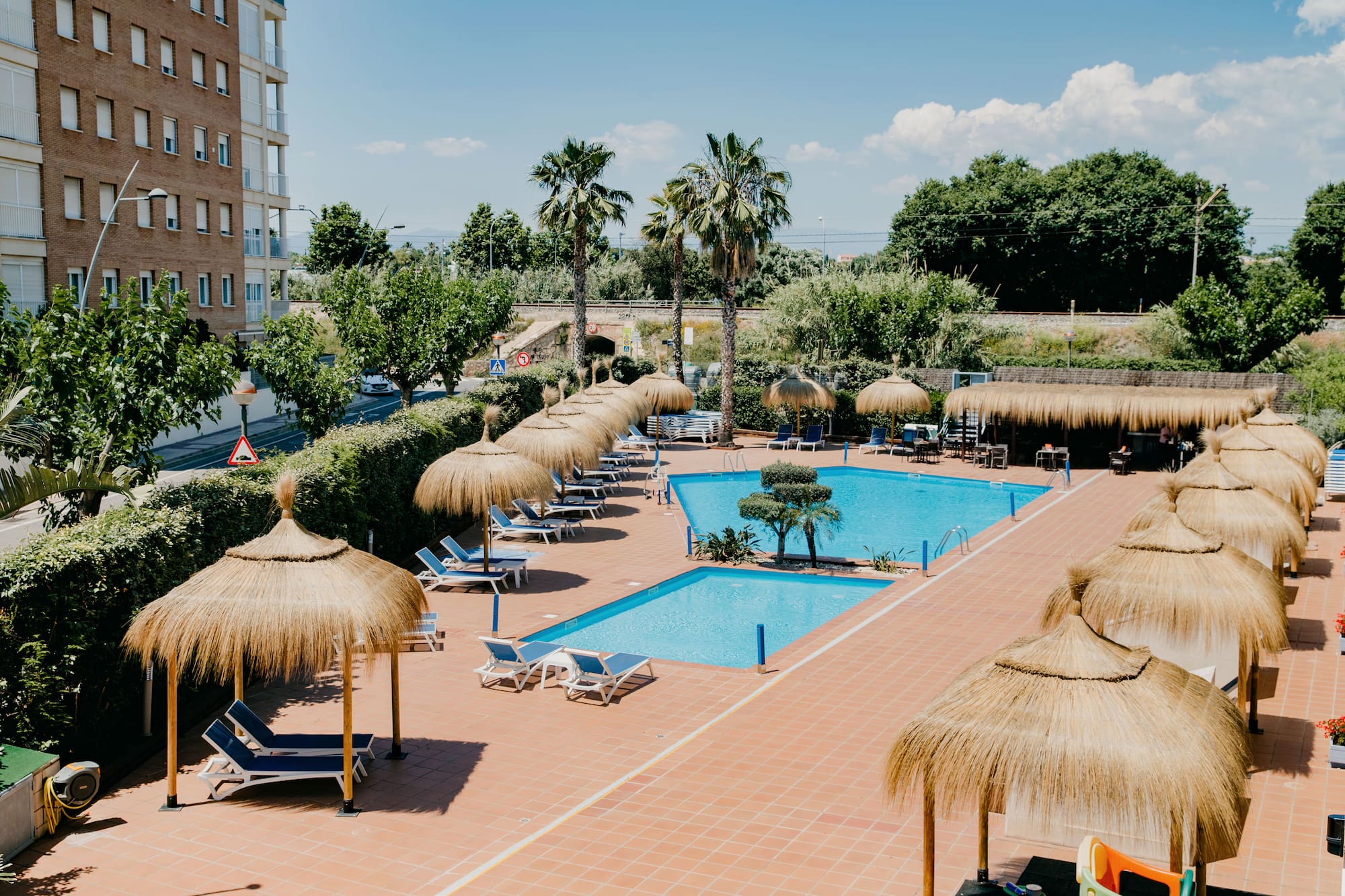 a pool with straw umbrellas and chairs