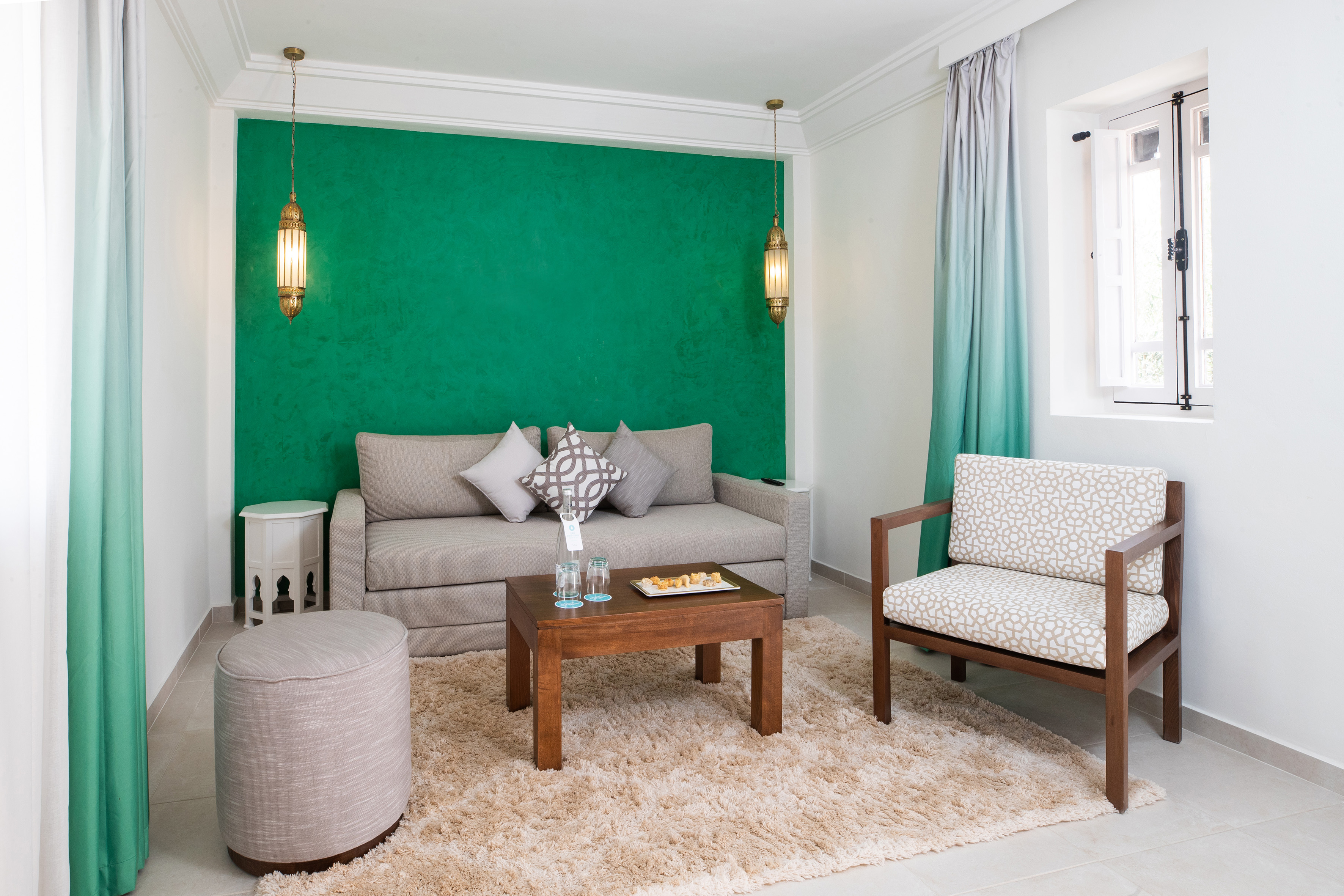Living room with green accent wall, sofa, armchair, and Moroccan lanterns. - Family Room - SOL Oasis Marrakech, Marrakech
