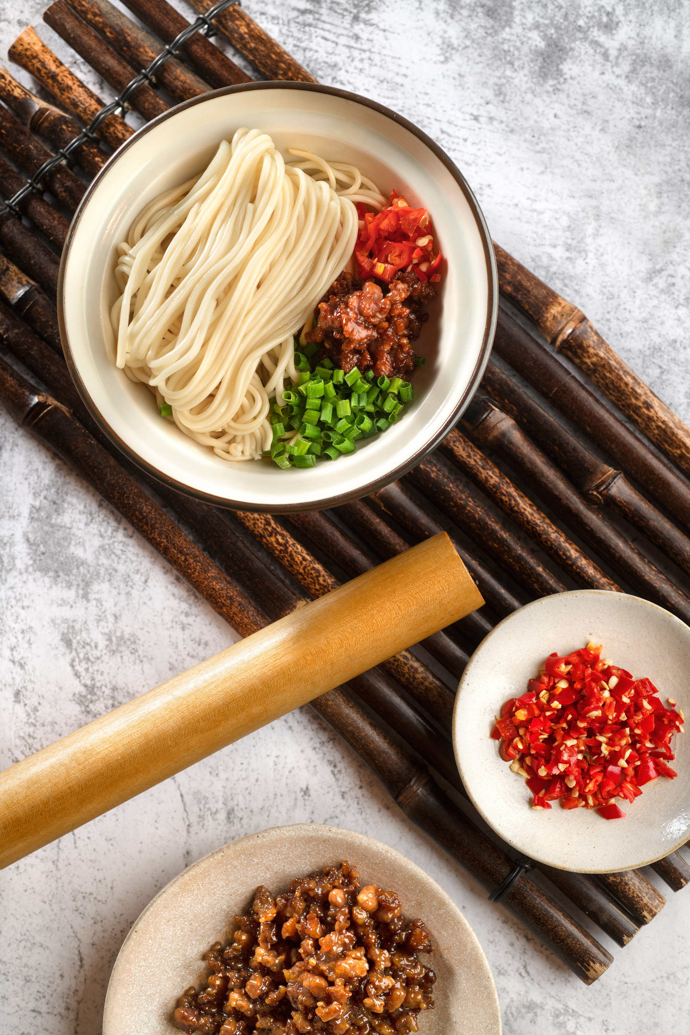 Chinese noodles bowl with minced meat, chopped chilies, and green onions.