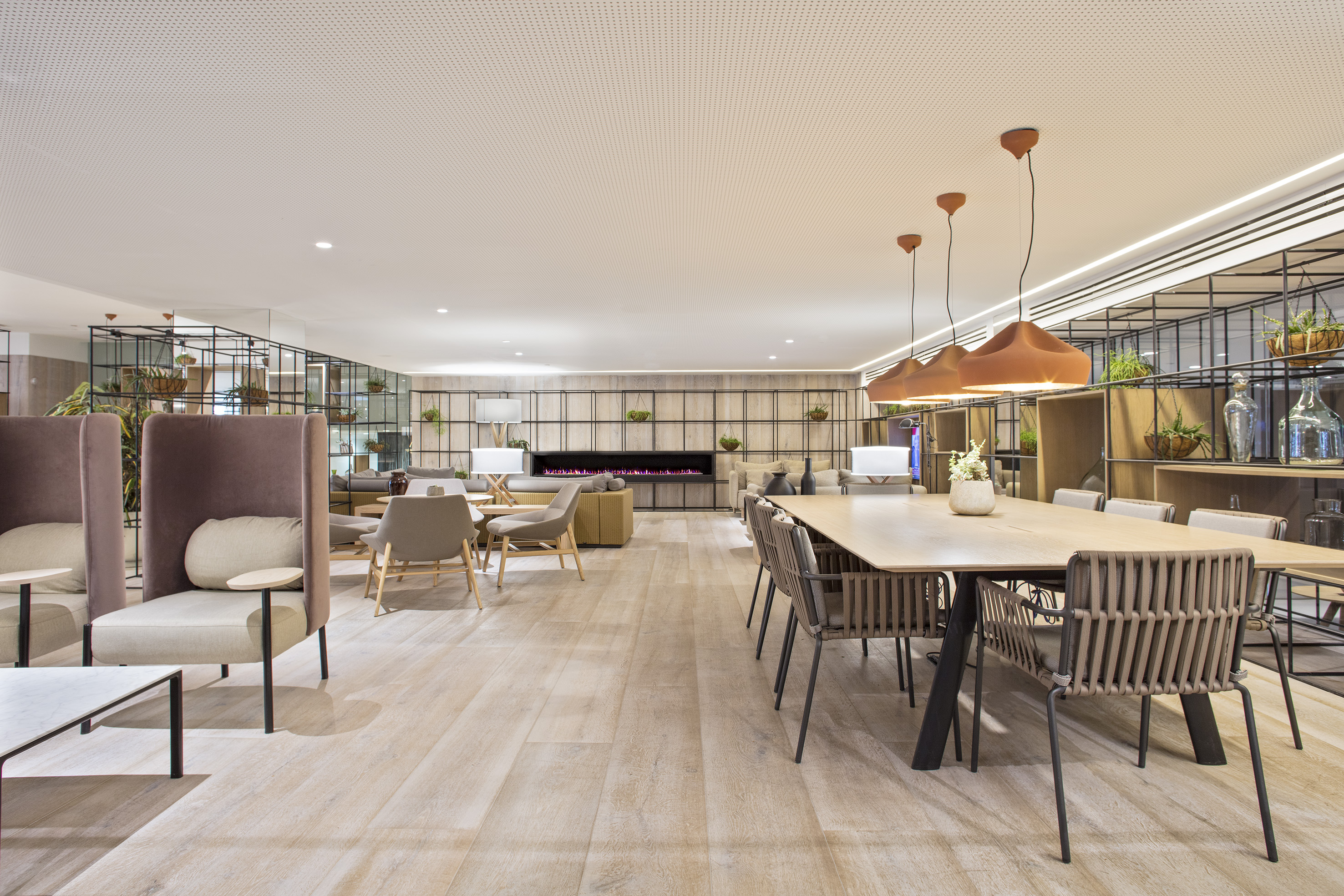 Stylish coworking lounge with varied seating, large table, and modern fireplace.