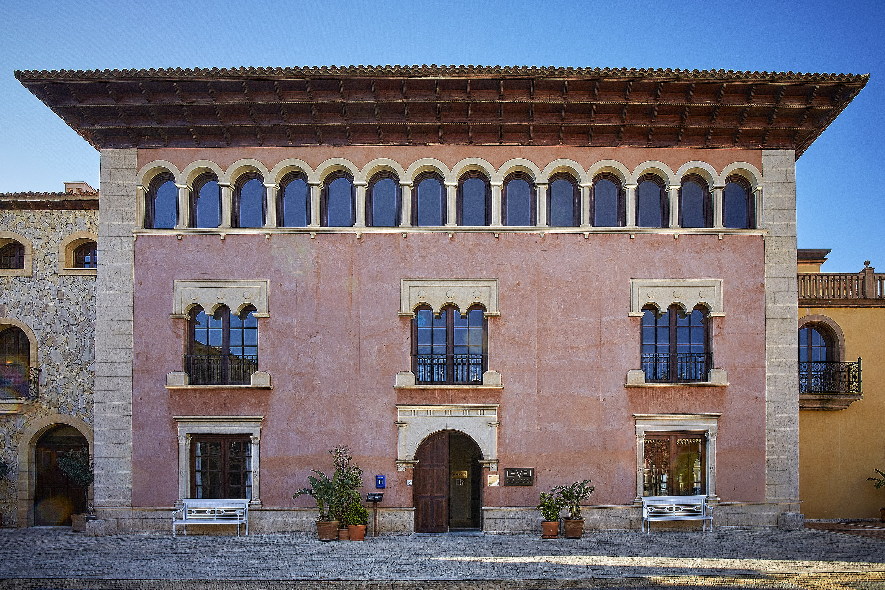 Levej Hotel: Pink Mediterranean building, arched windows, tiled roof.