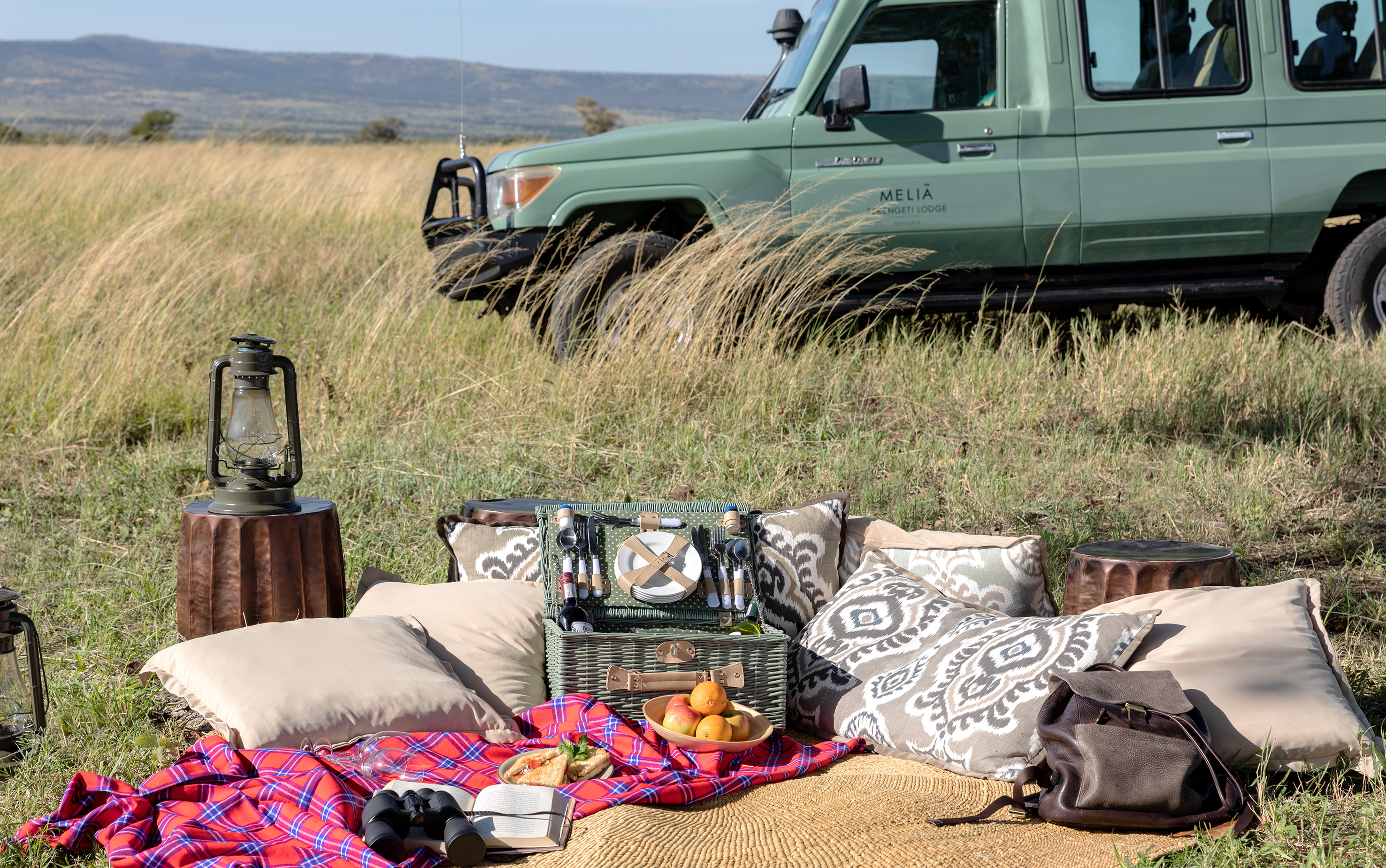 Serengeti safari picnic with luxury setup and Melia Lodge game drive vehicle.