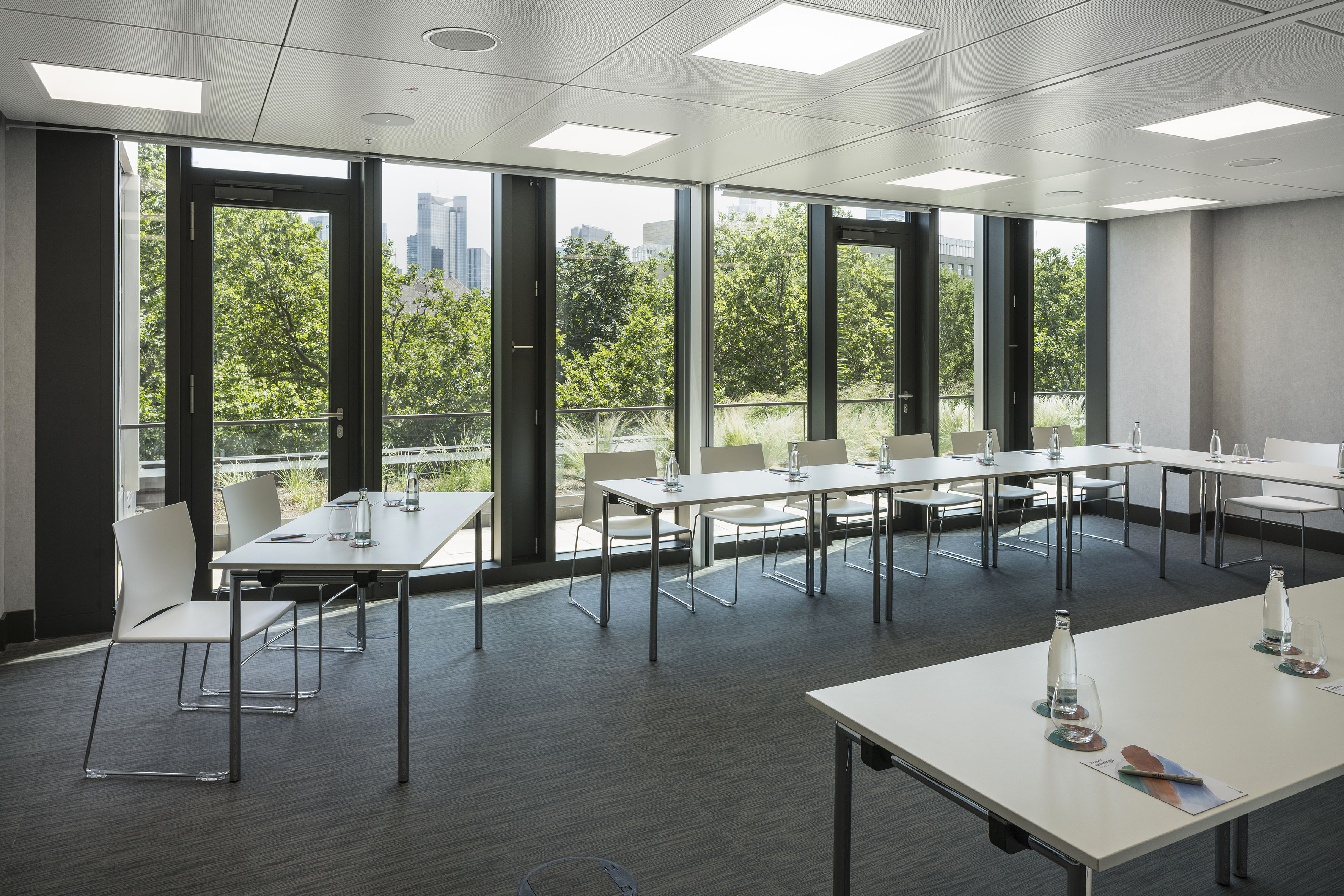 Bright modern meeting room with city view and U-shaped table setup.