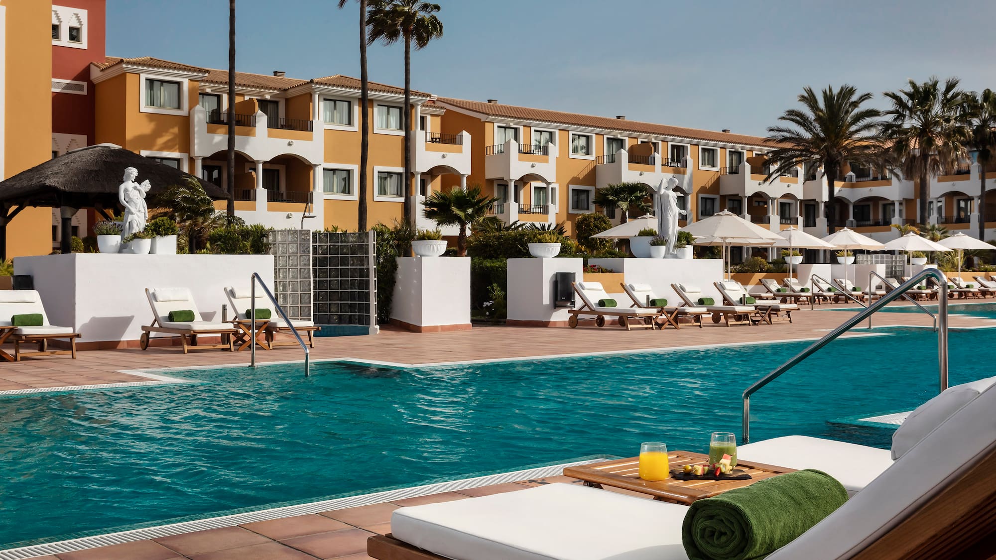 a pool with lounge chairs and a statue in the background
