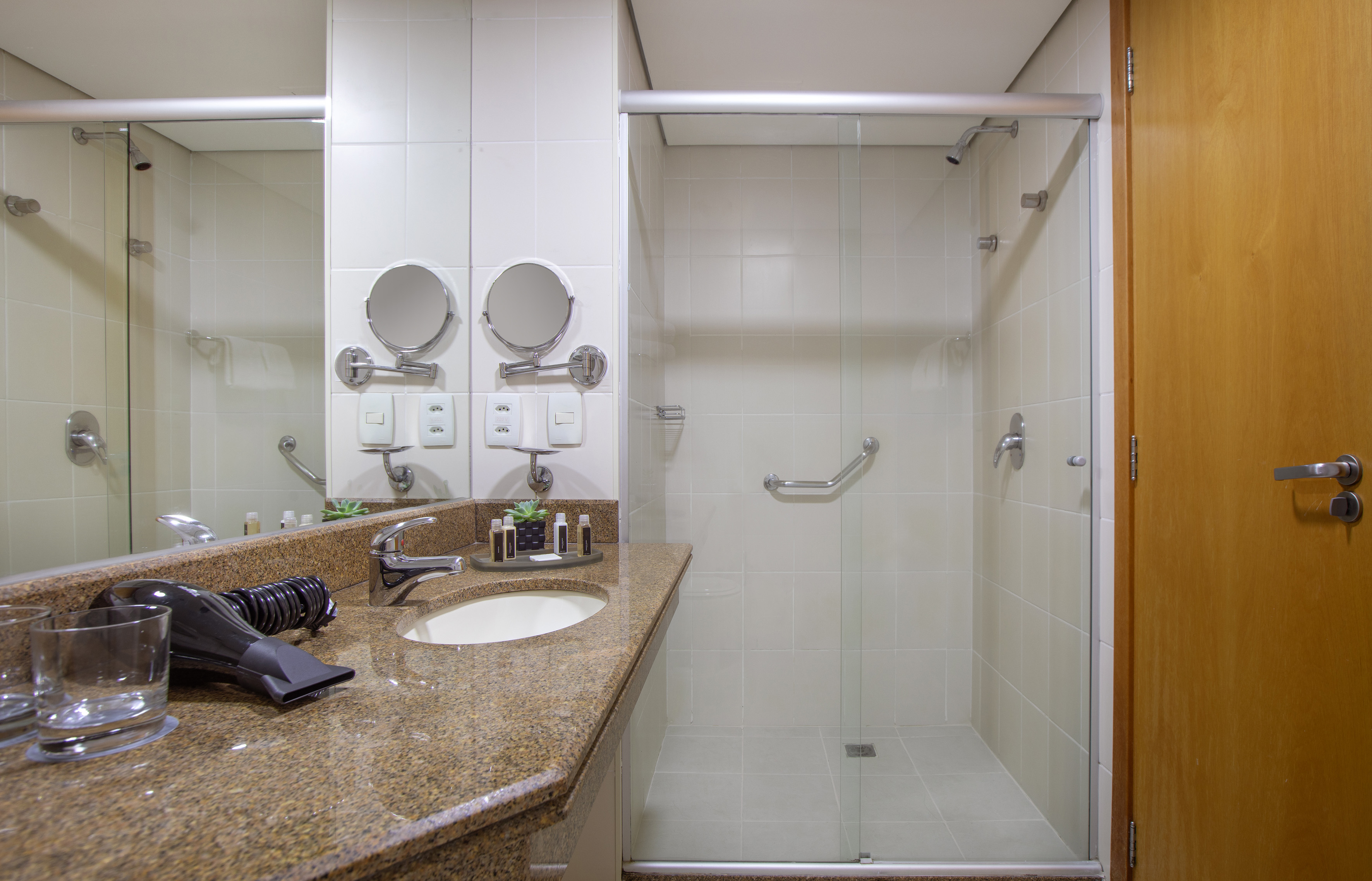 Modern bathroom with granite vanity, sink, mirror, and glass shower.