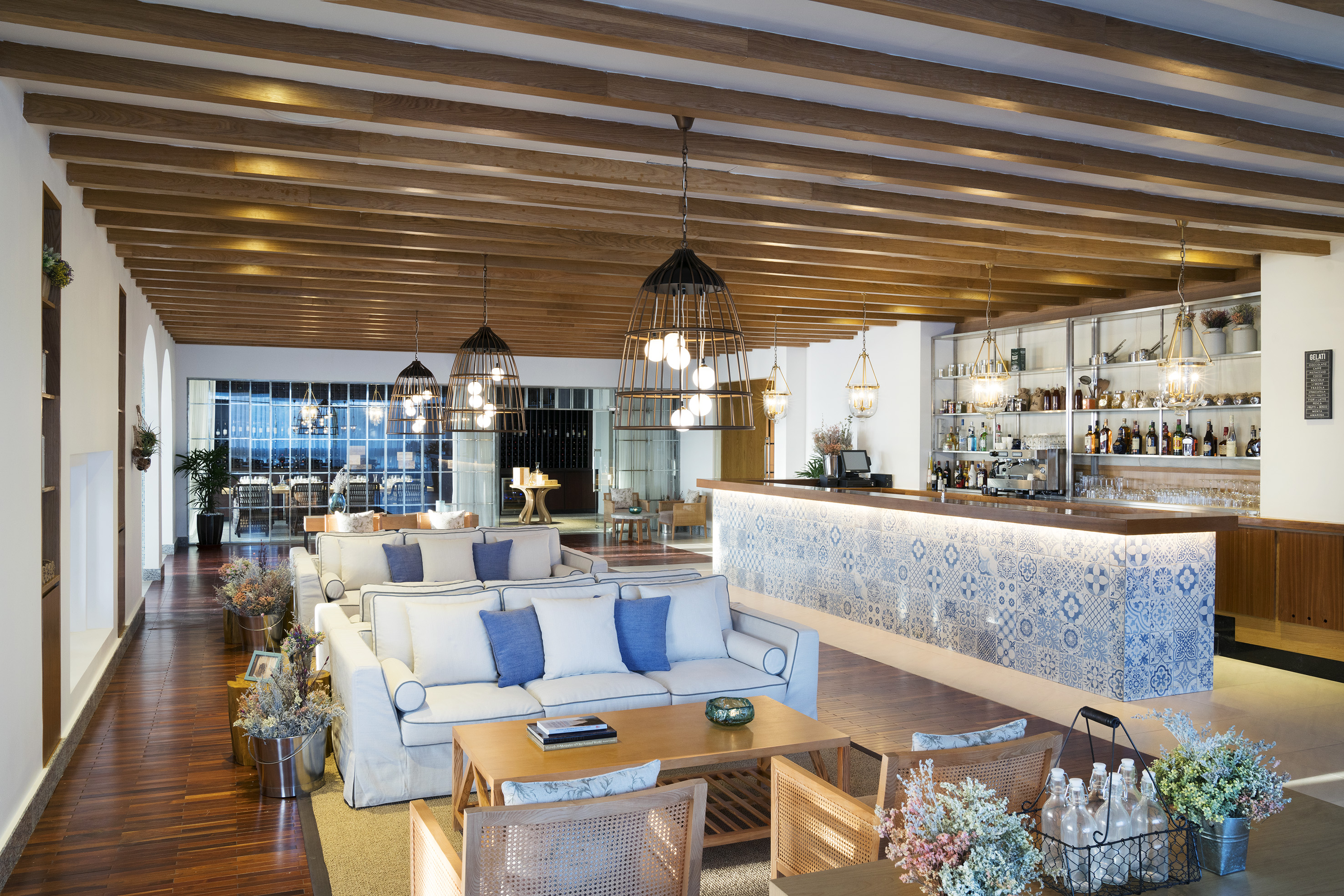Modern hotel lounge with tiled bar, beamed ceiling, and white sofas.