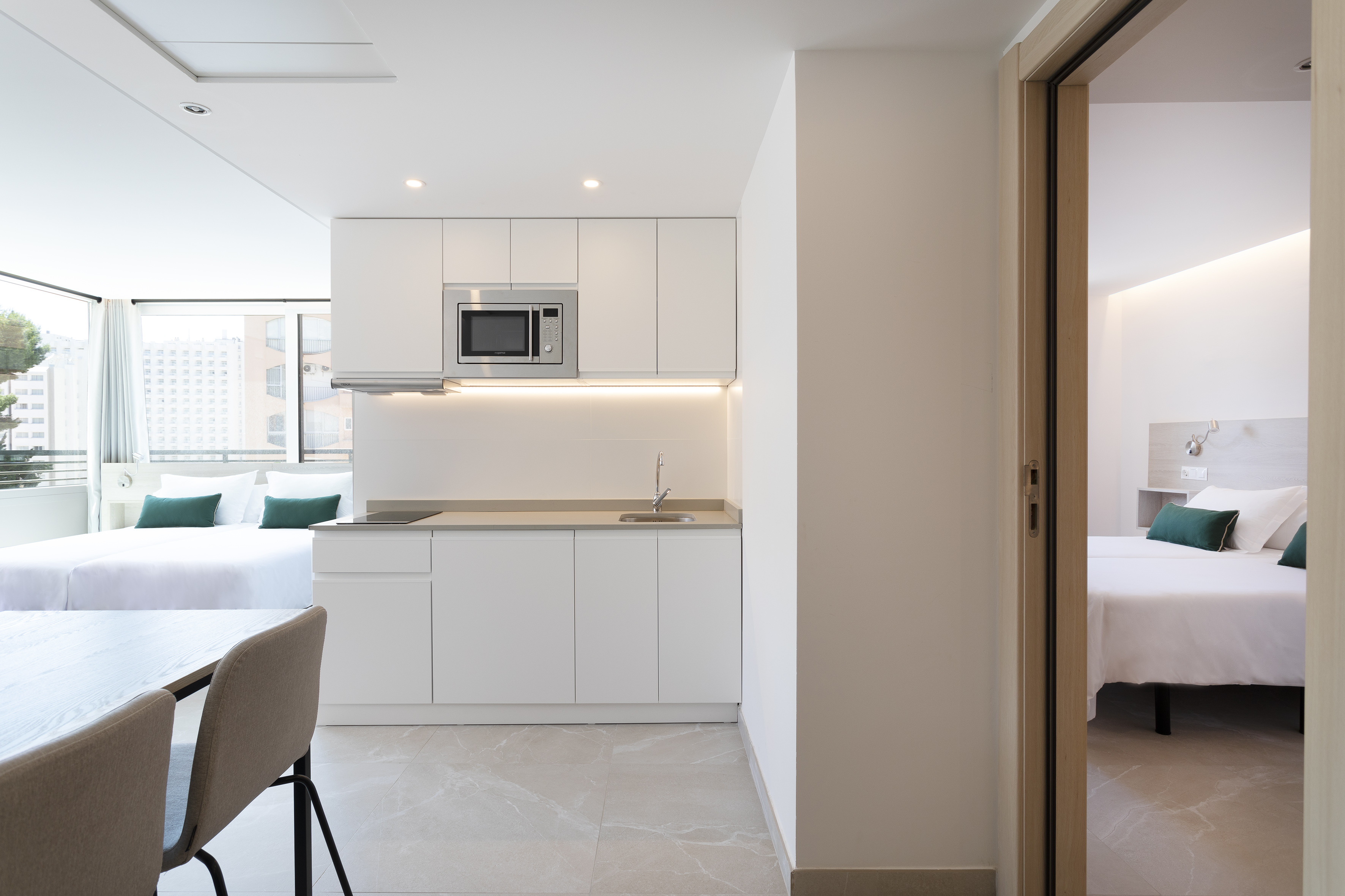 Modern apartment: kitchen, dining area, bed, and bedroom access.