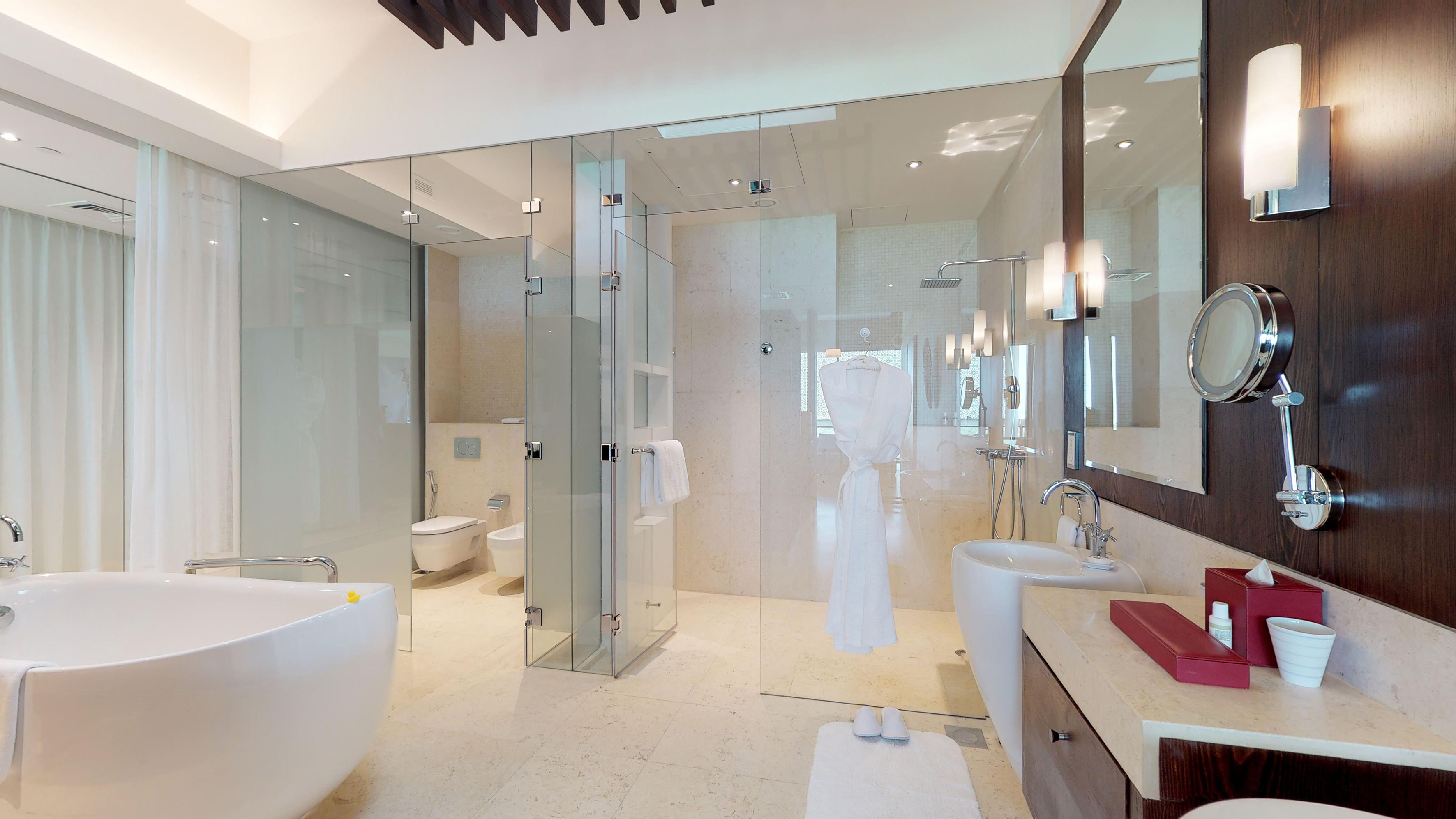 Elegant hotel bathroom with freestanding tub, walk-in shower, and marble vanity.
