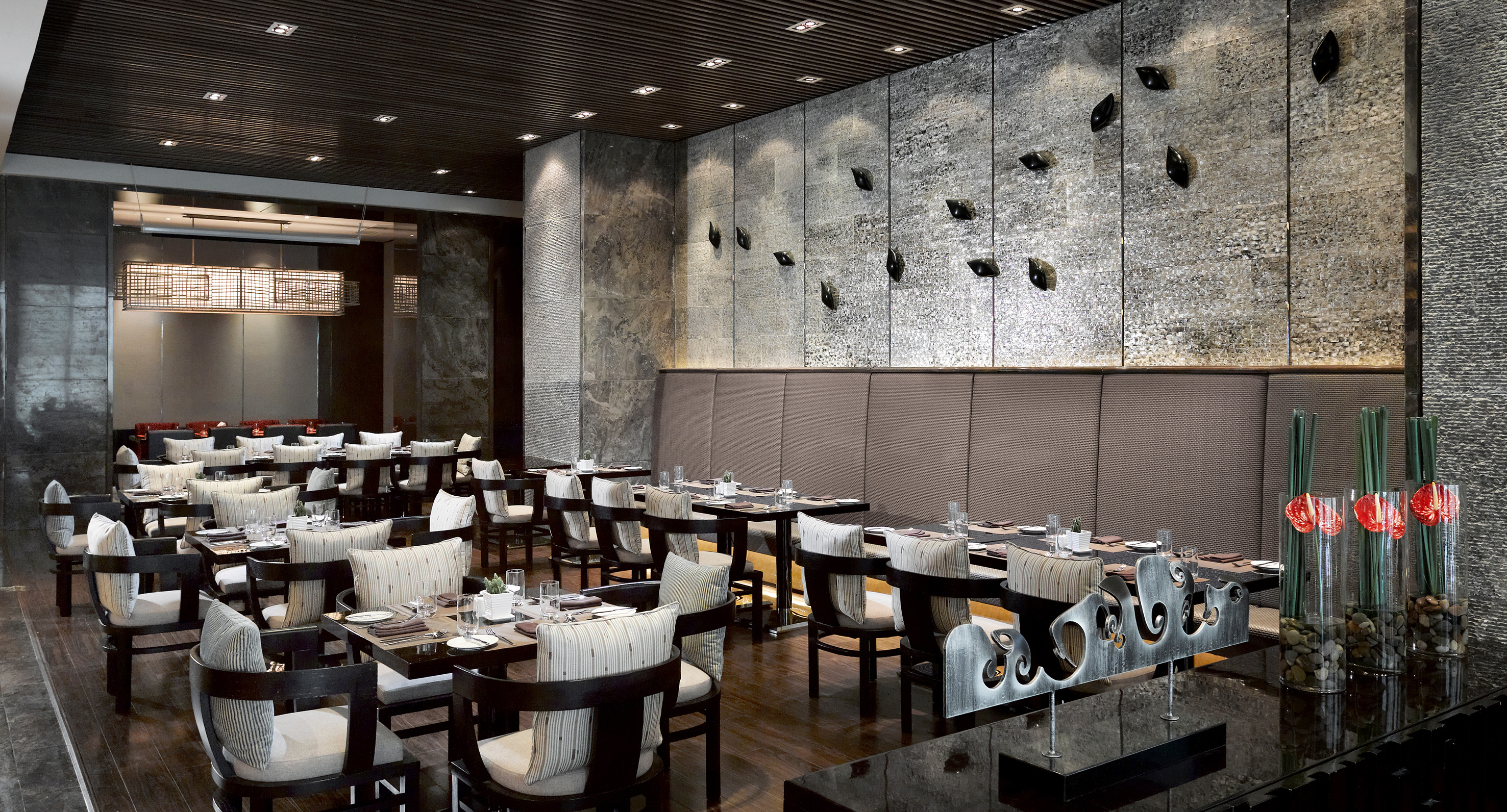Modern upscale restaurant interior with set dining tables and textured walls.