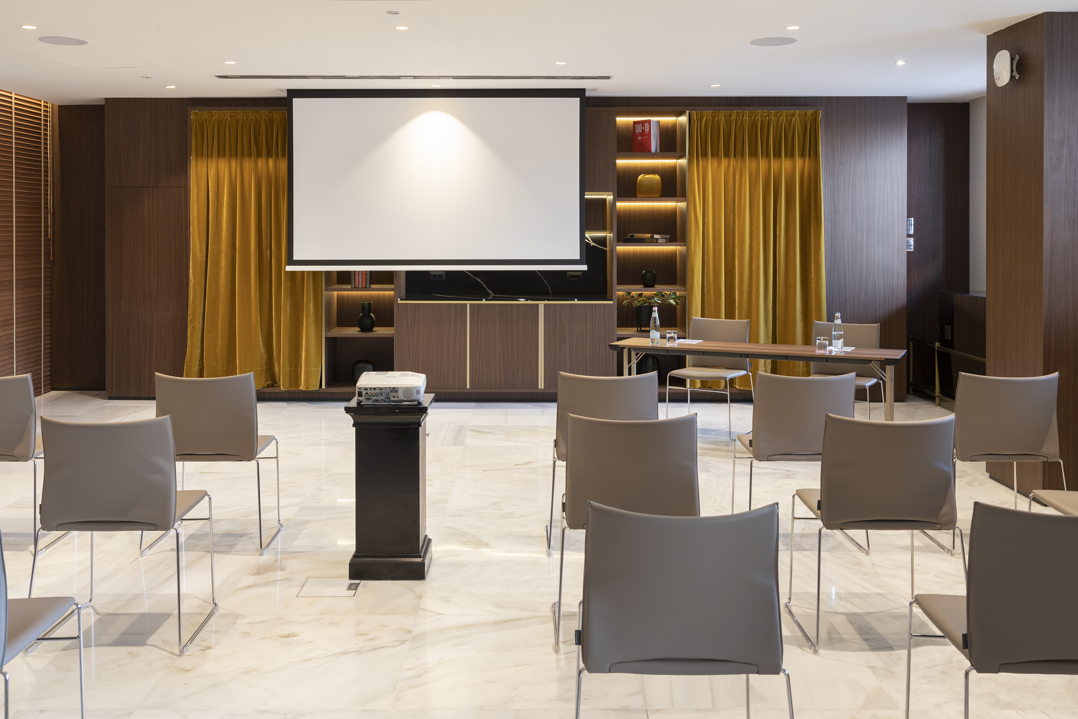 Elegant presentation room with projector screen, seating, and wooden decor.