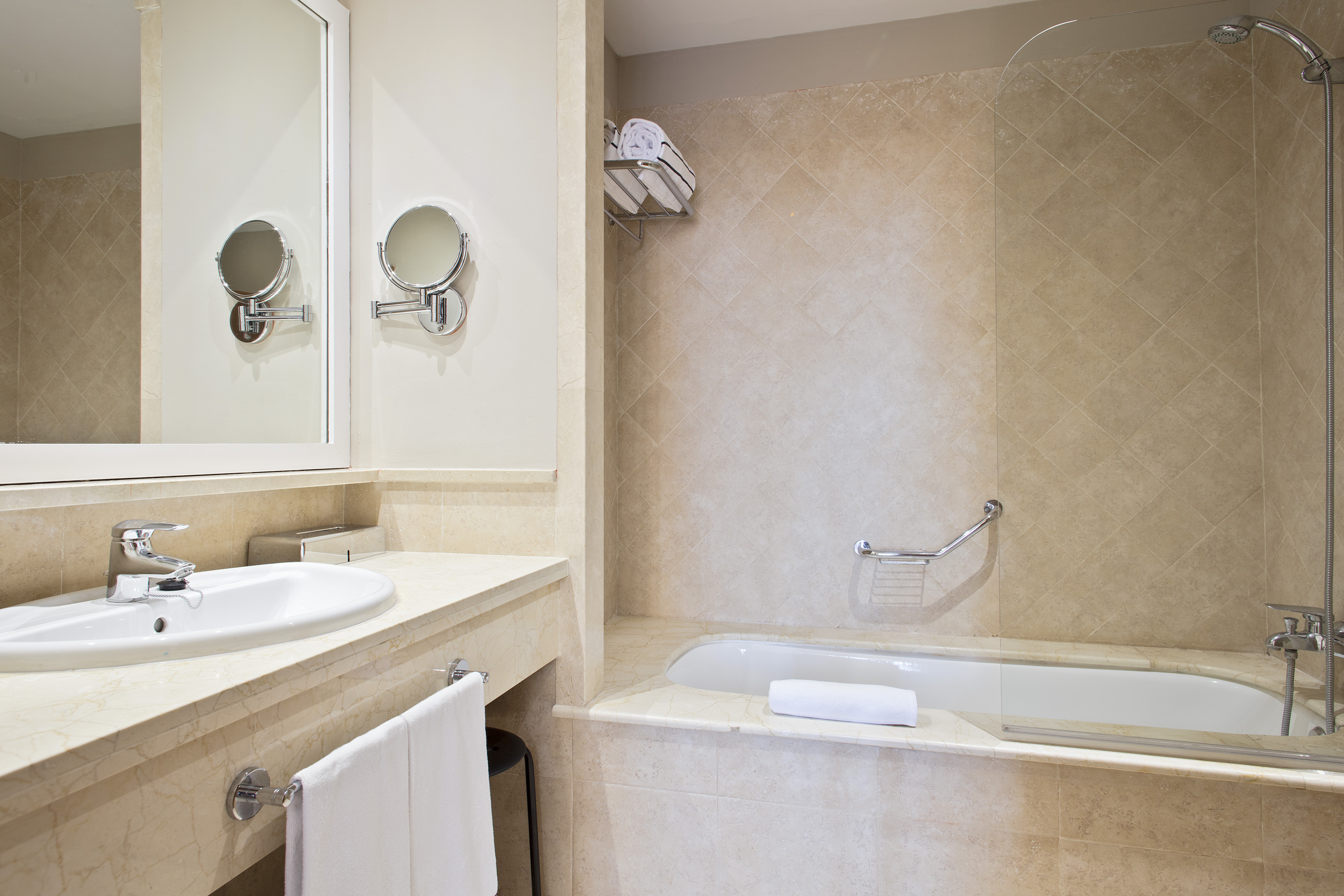 Modern beige tiled bathroom with vanity, sink, bathtub, and shower.