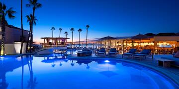 a pool with lounge chairs and umbrellas and a beach bar