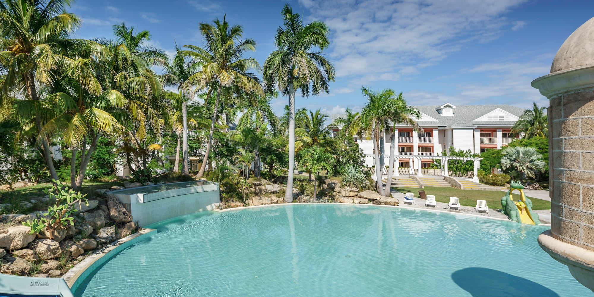 a pool with palm trees and a building in the background