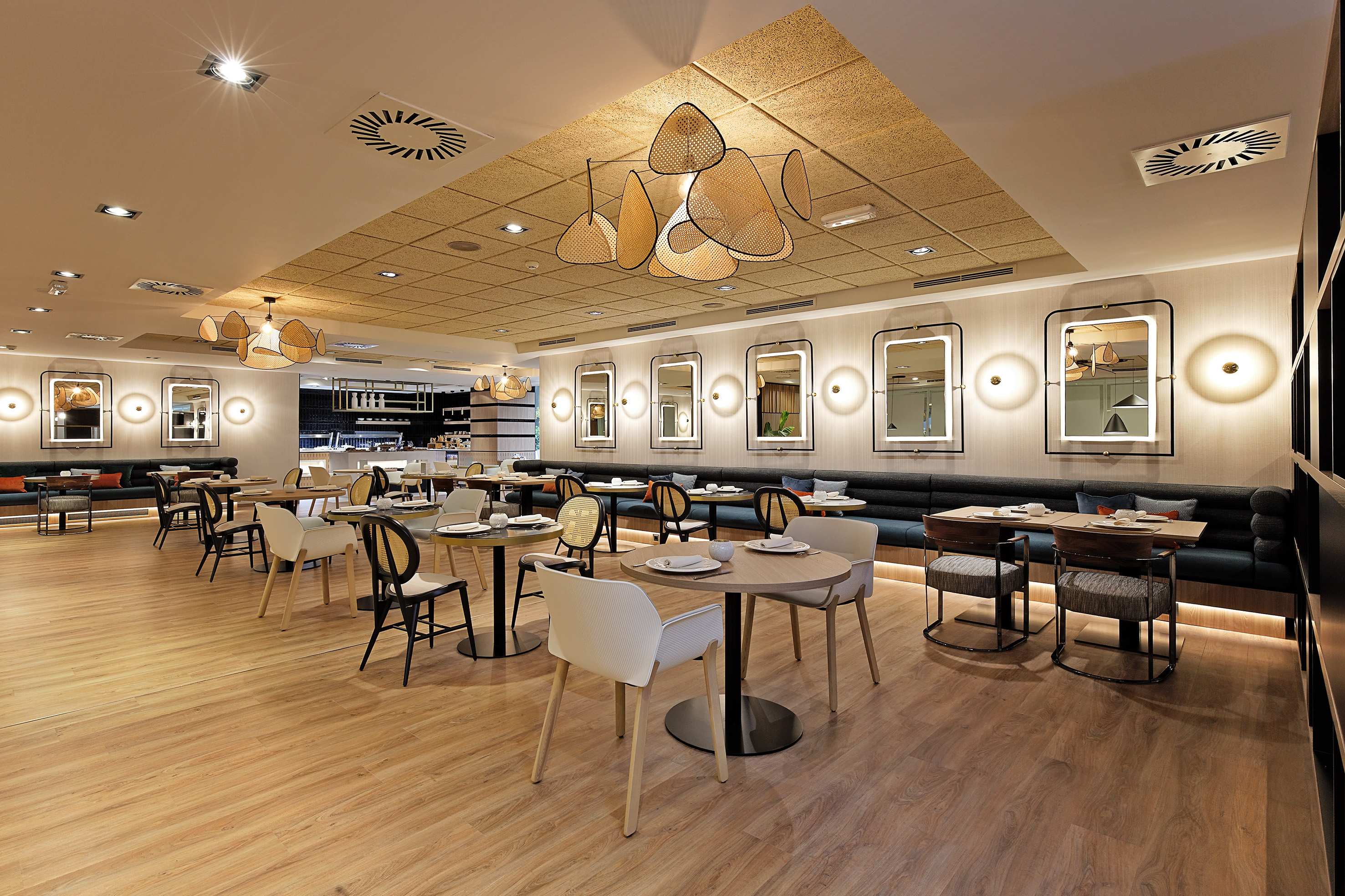 Stylish restaurant interior with tables, banquettes, wall mirrors, and rattan lights.