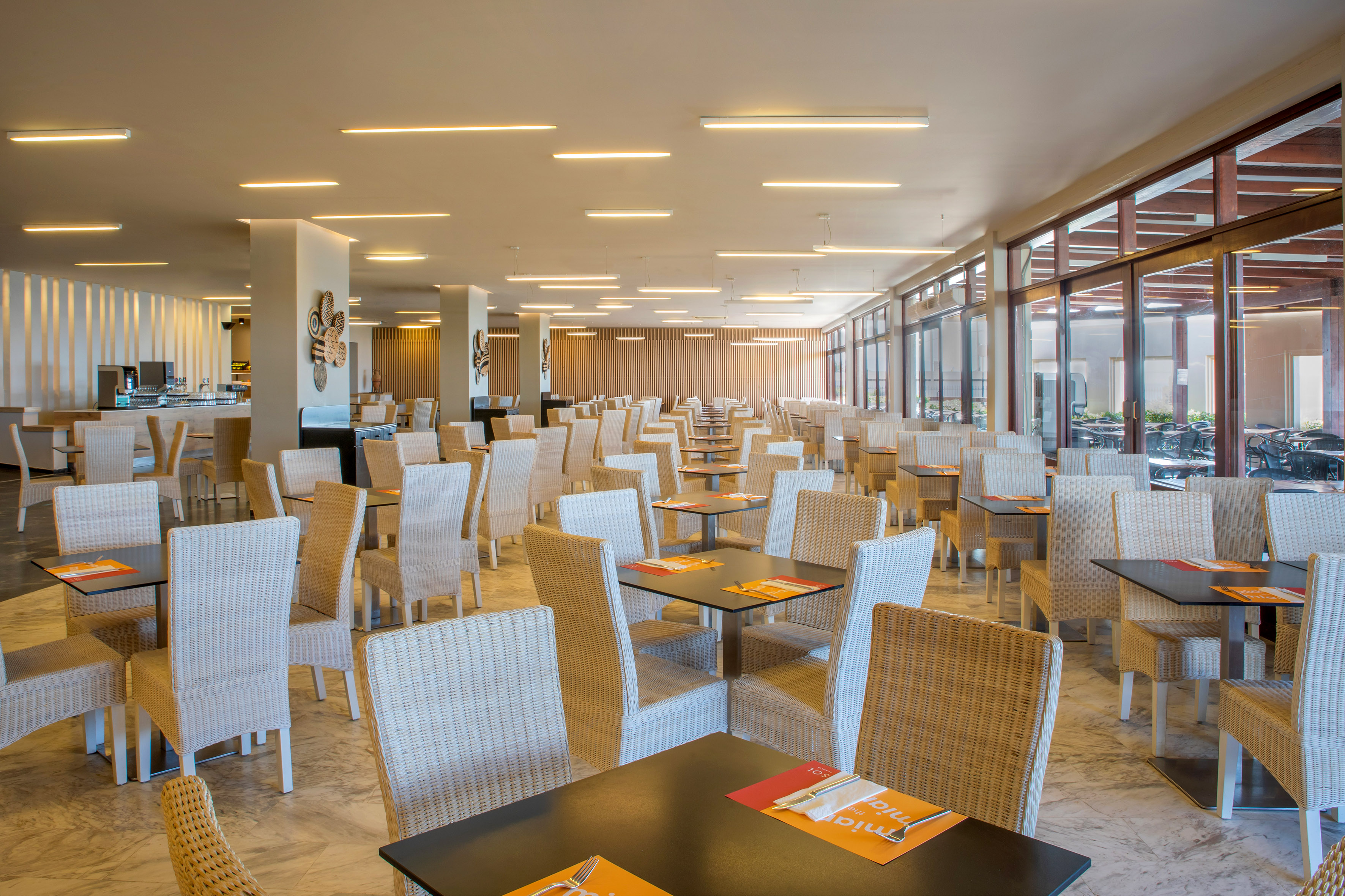 Modern resort buffet restaurant with many tables and wicker chairs.