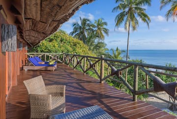 a deck with chairs and a thatched roof overlooking the ocean