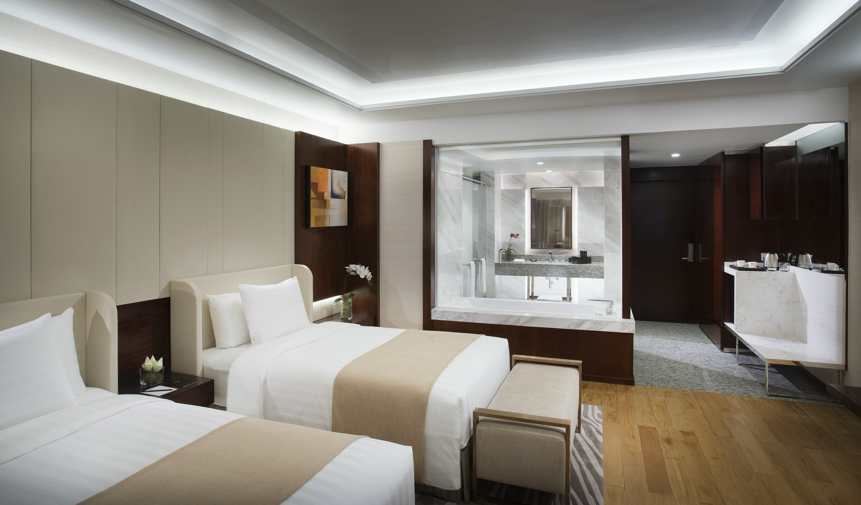 Modern hotel room with two twin beds and open-concept marble bathroom.