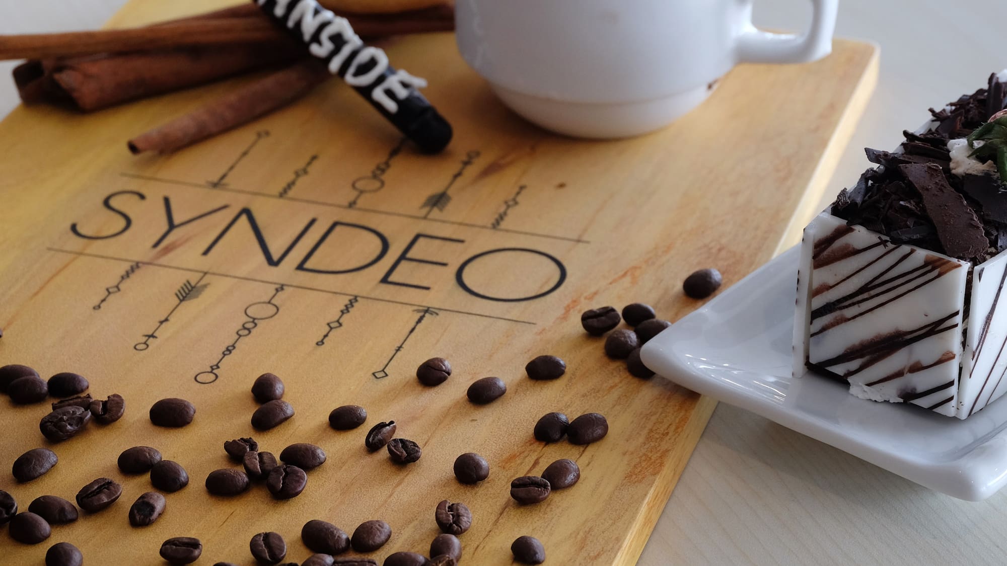 a coffee cup and a plate of coffee beans and a piece of cake