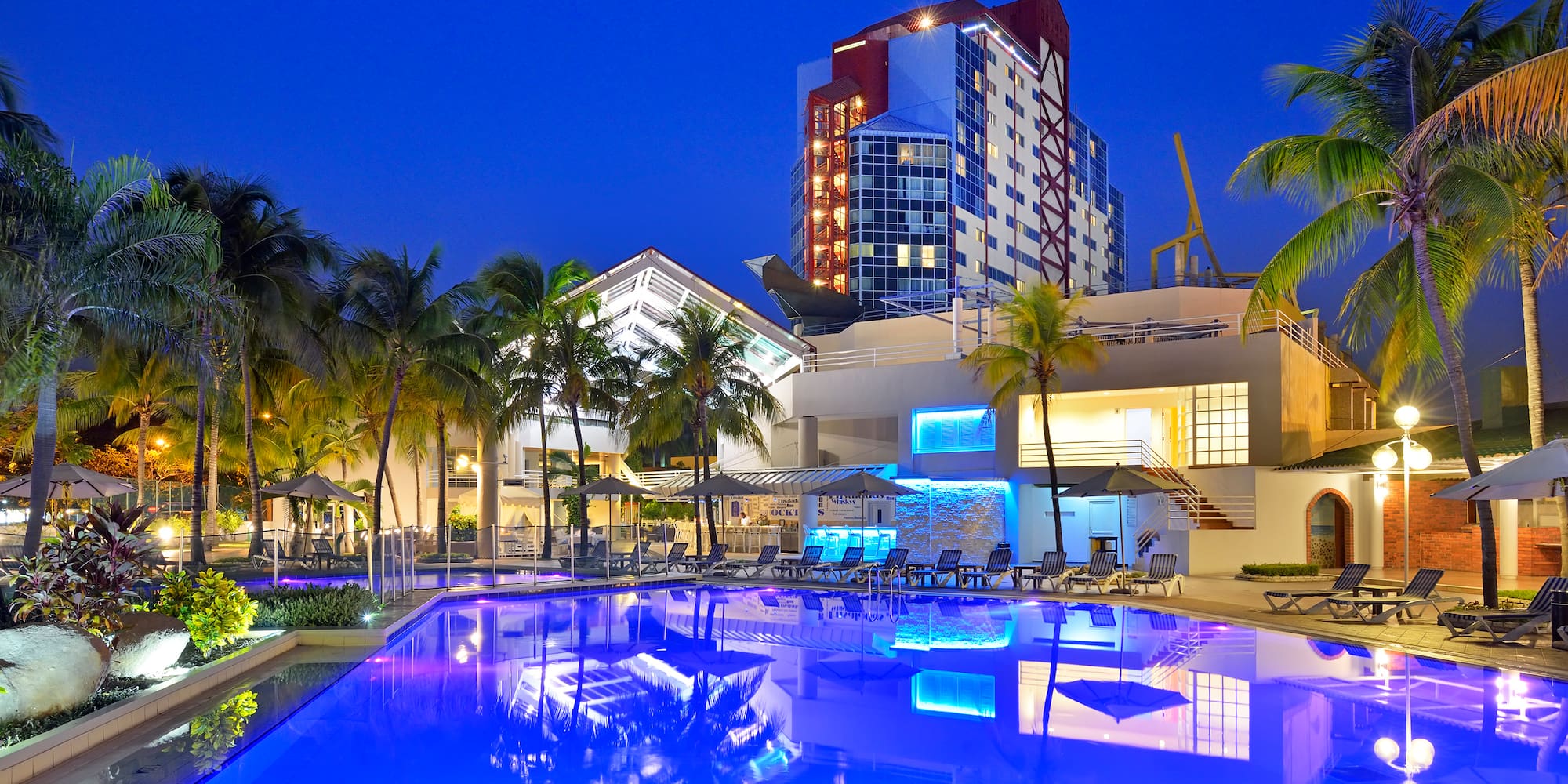 a pool with palm trees and a building in the background