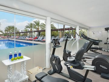 a room with exercise equipment and a pool