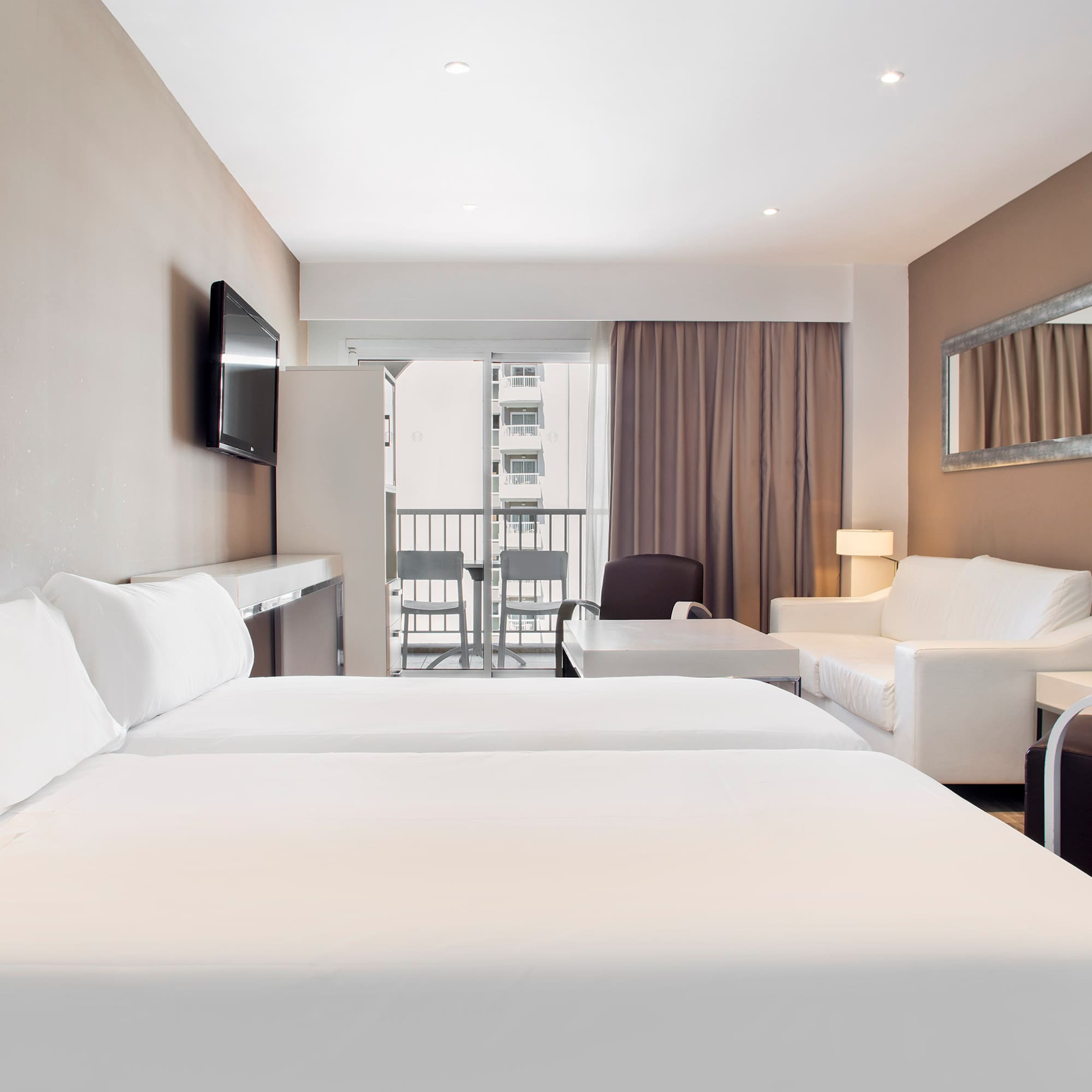 a room with white beds and a television