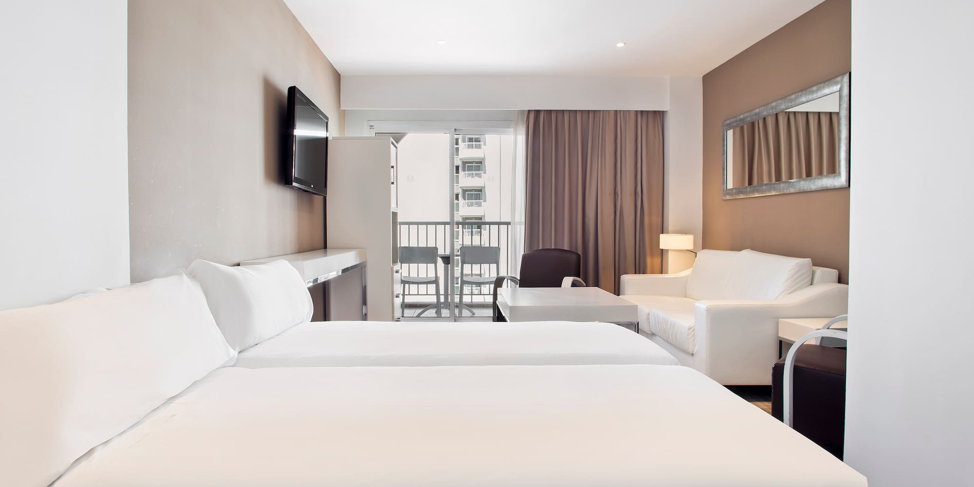 a room with white beds and a television