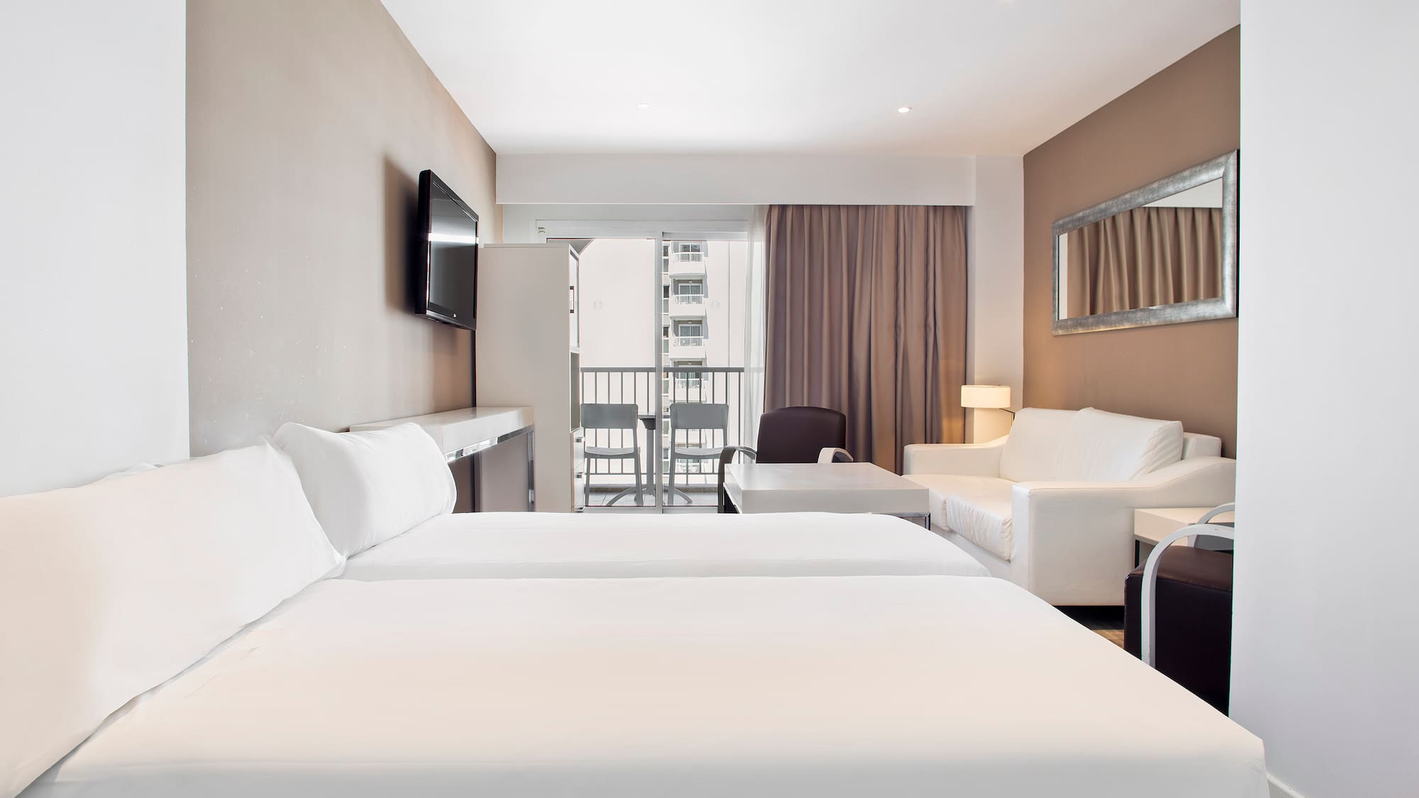 a room with white beds and a television