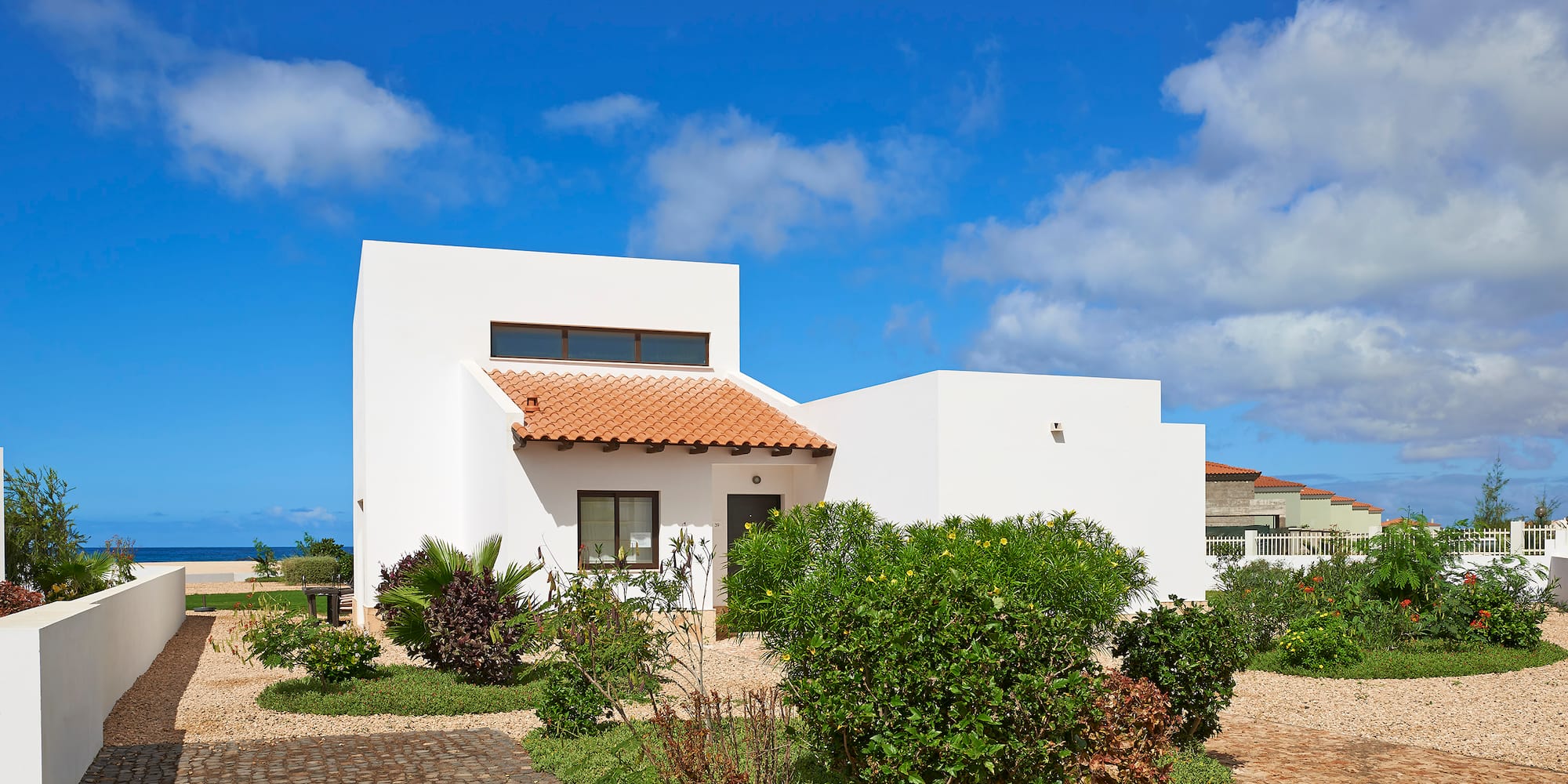 a white house with a garden and blue sky