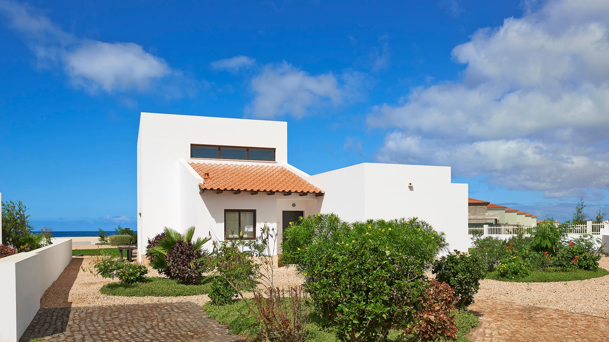 a white house with a garden and blue sky
