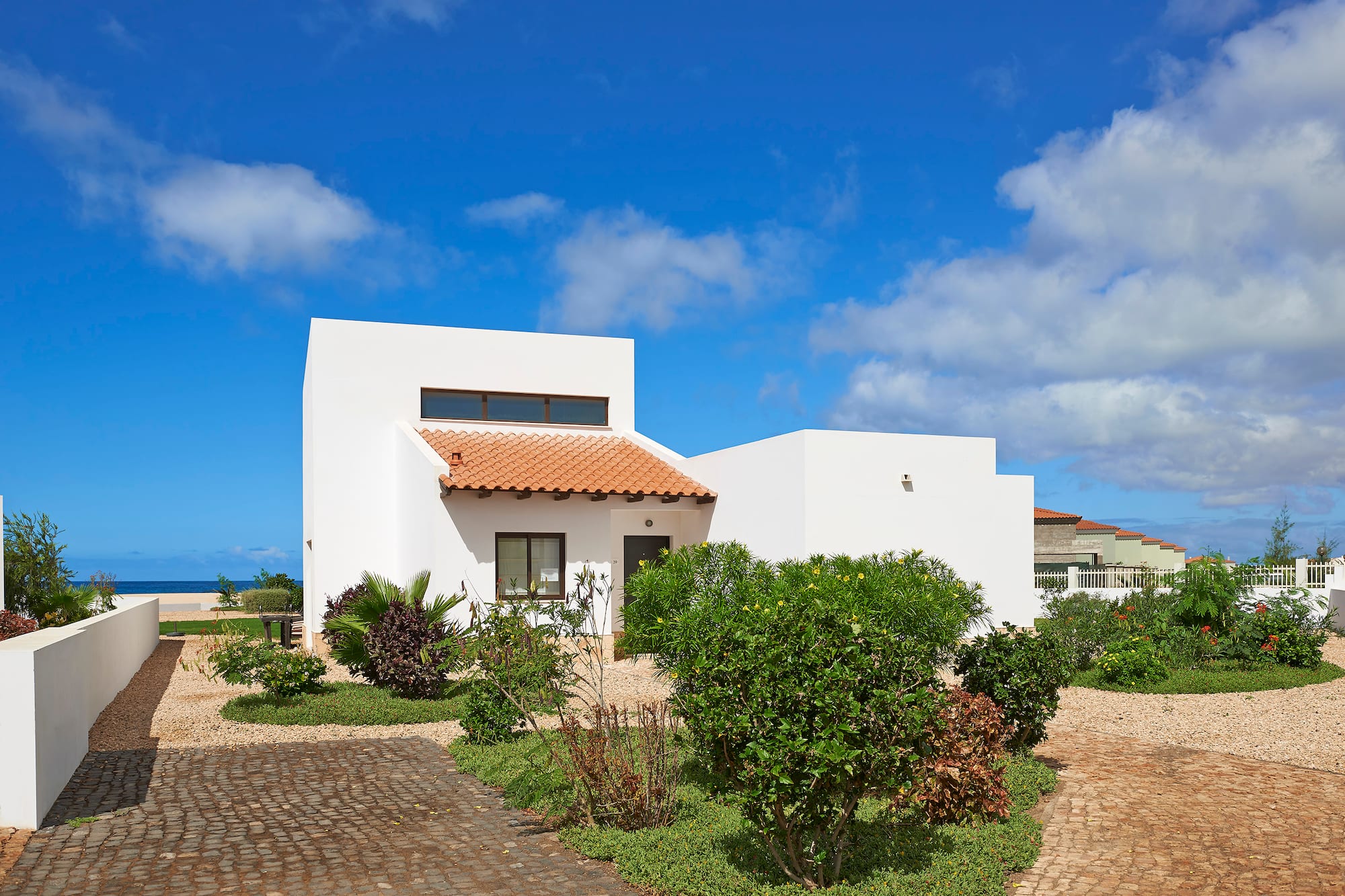 a white house with a garden and blue sky
