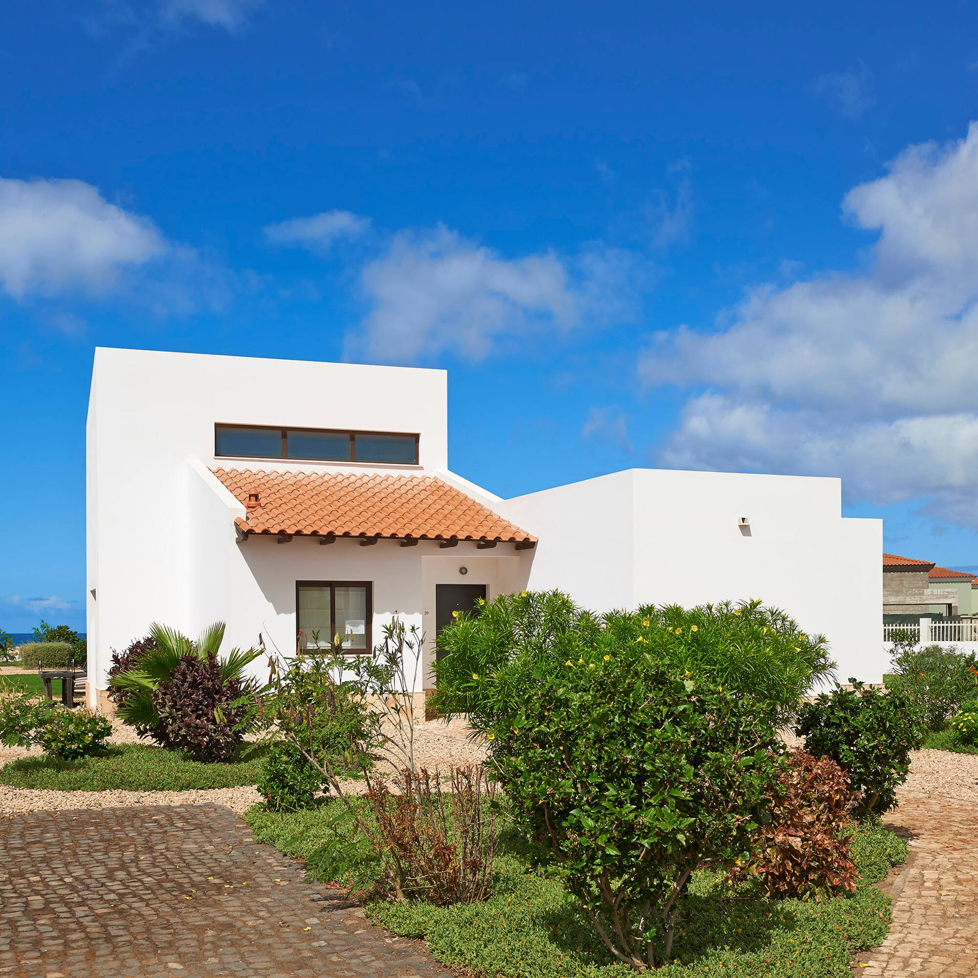 a white house with a garden and blue sky