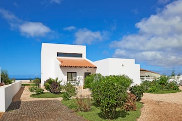 a white house with a garden and blue sky