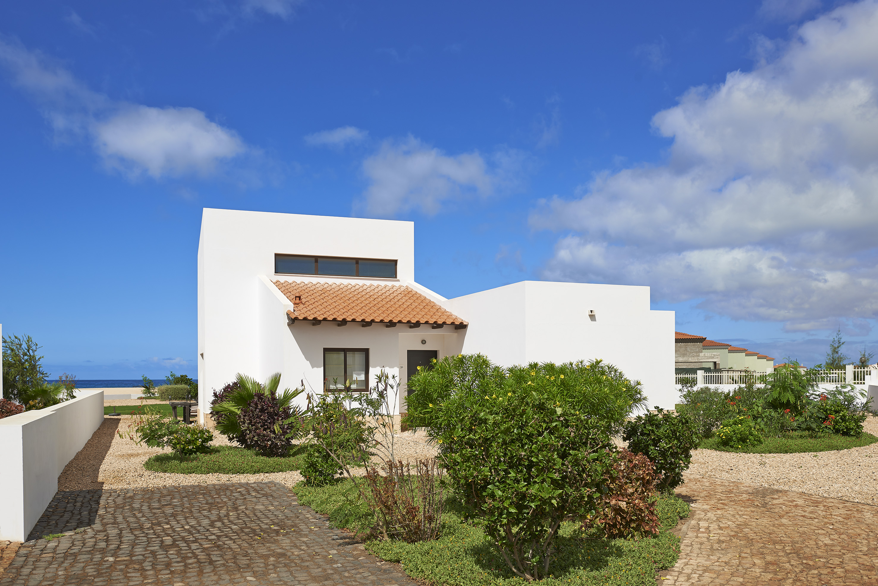 a white house with a garden and blue sky