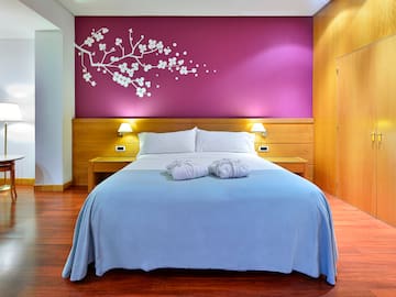a bed with a purple wall and wood floor