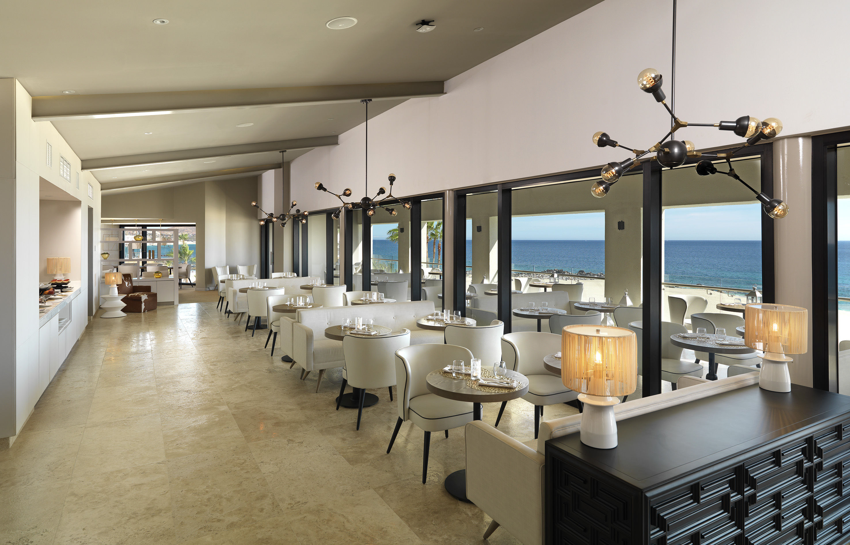 Modern oceanfront restaurant with set tables, contemporary decor, and sea views.