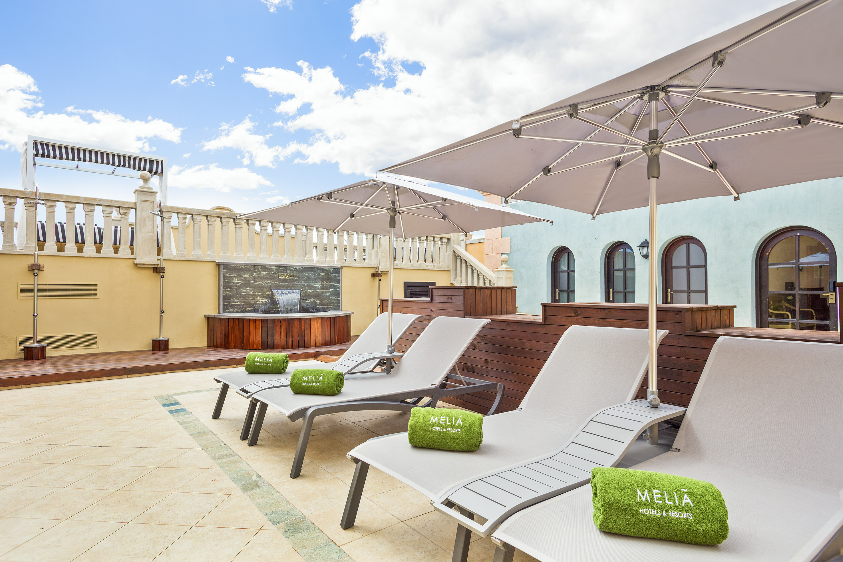 Meliá hotel terrace with sun loungers, umbrellas, and water feature.