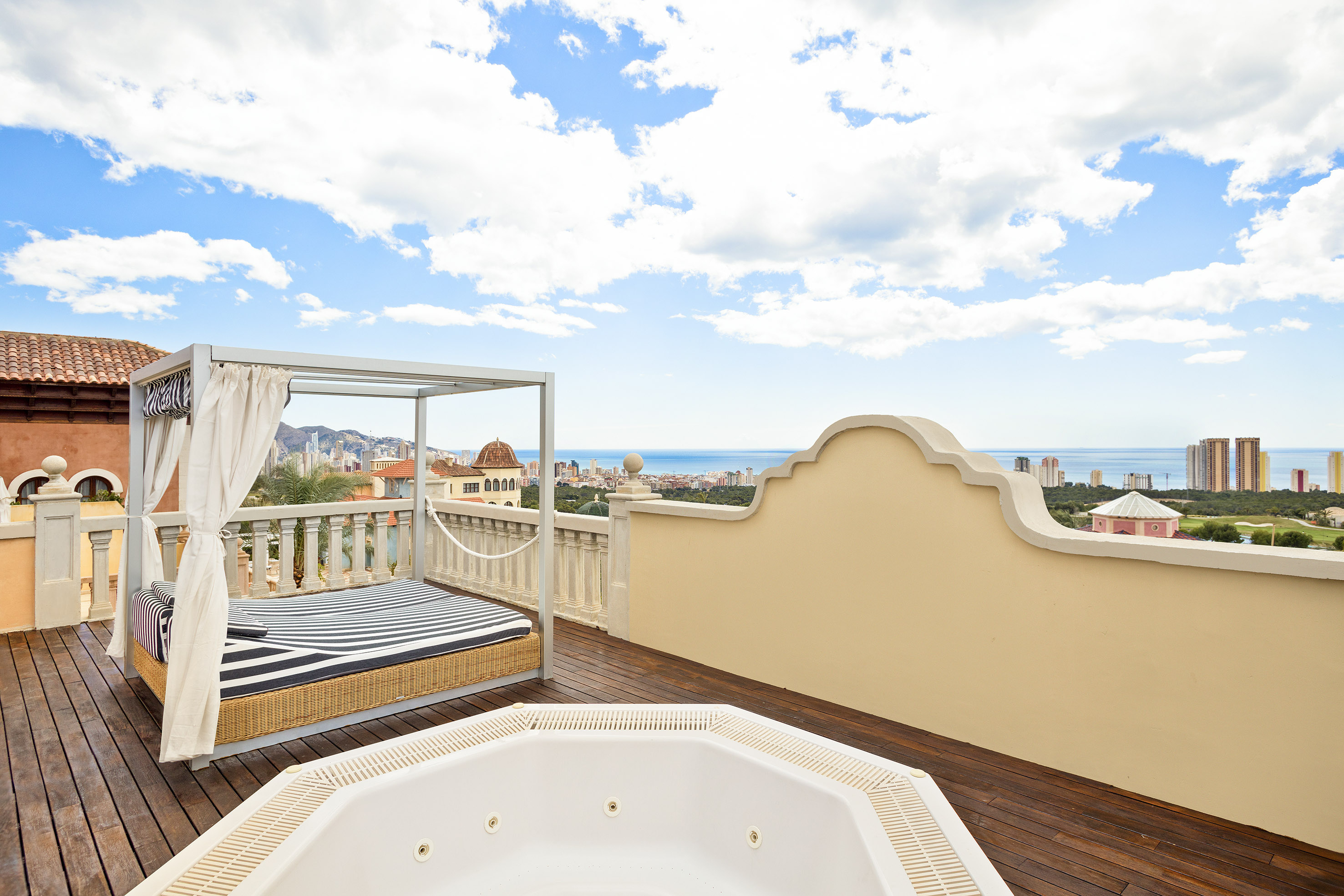 Luxury rooftop terrace with hot tub, canopy daybed, and stunning ocean city views.
