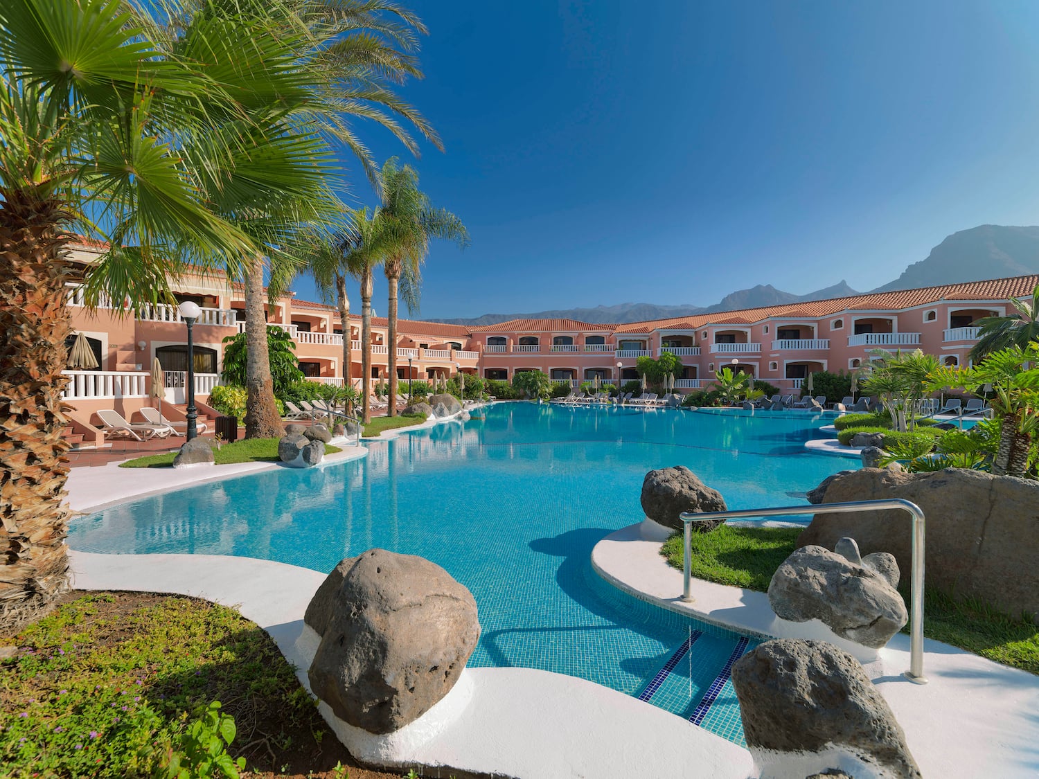 a pool with palm trees and a building