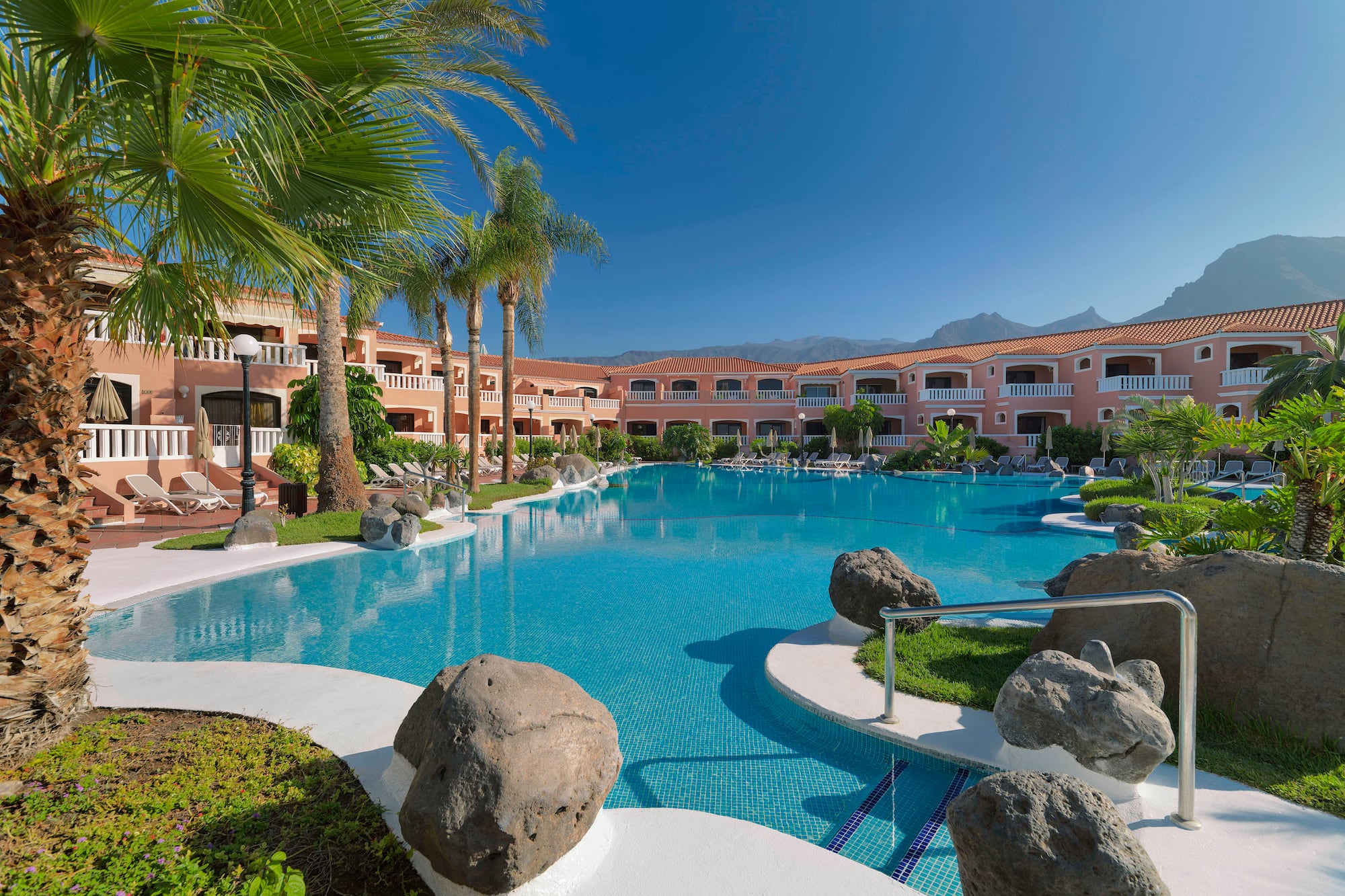 a pool with palm trees and a building